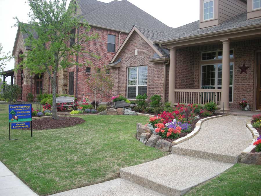 Green lawn and small garden next to a paved walkway