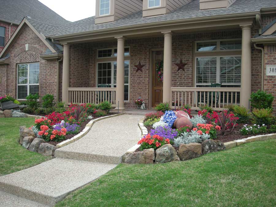 Paved entryway into a home with a flower garden on either side
