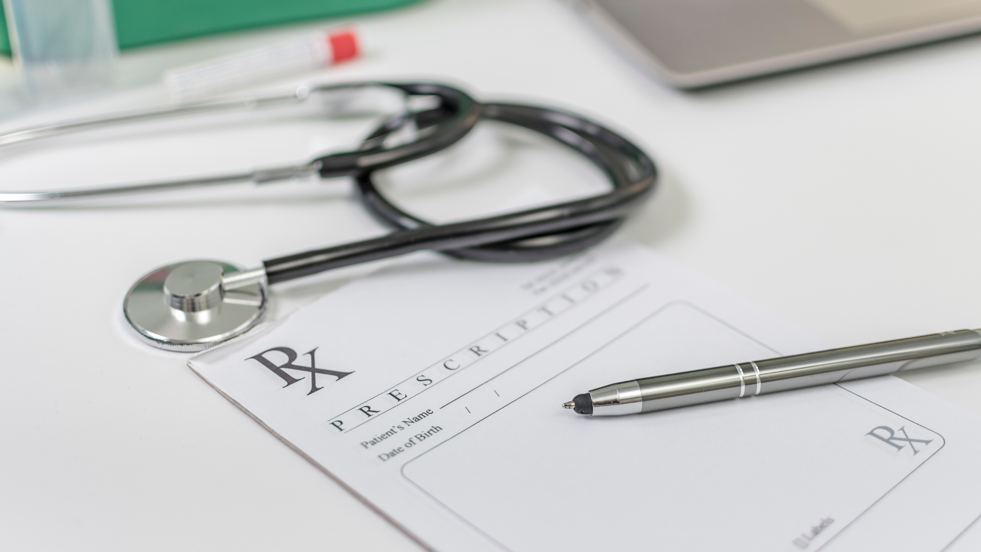 A stethoscope is sitting on top of a prescription form next to a pen.