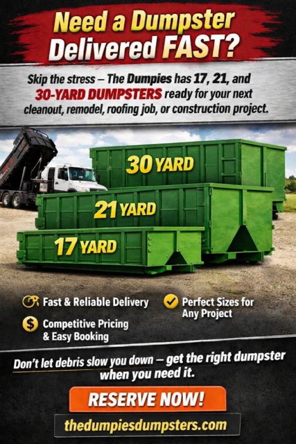 A large black dumpster is sitting on top of a dirt road.