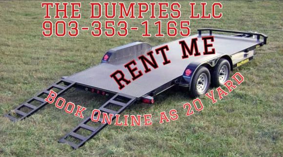 A large black dumpster is sitting on top of a dirt road.