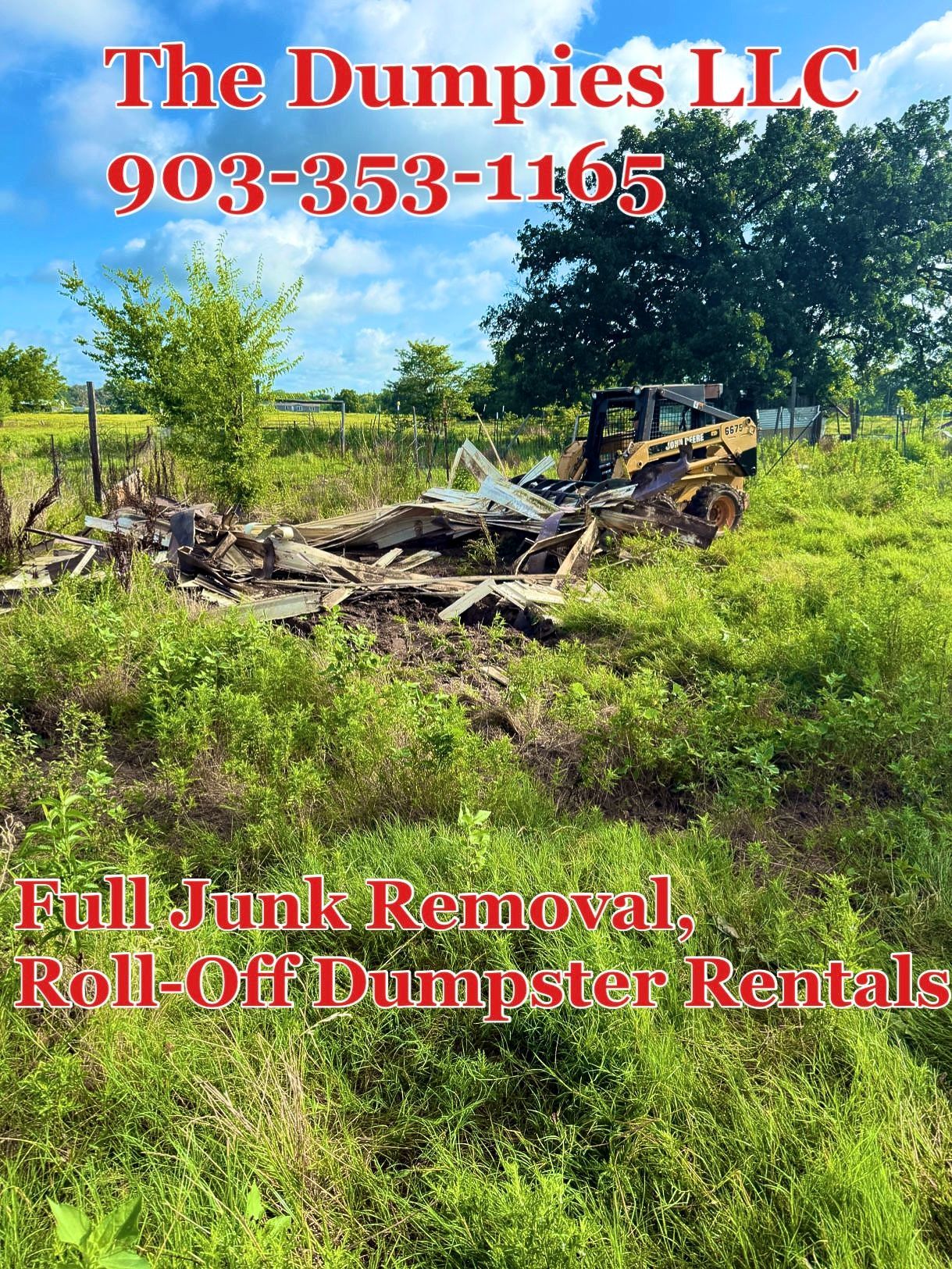 A large black dumpster is sitting on top of a dirt road.