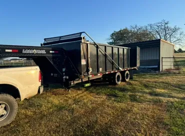 A truck is towing a trailer in a field.