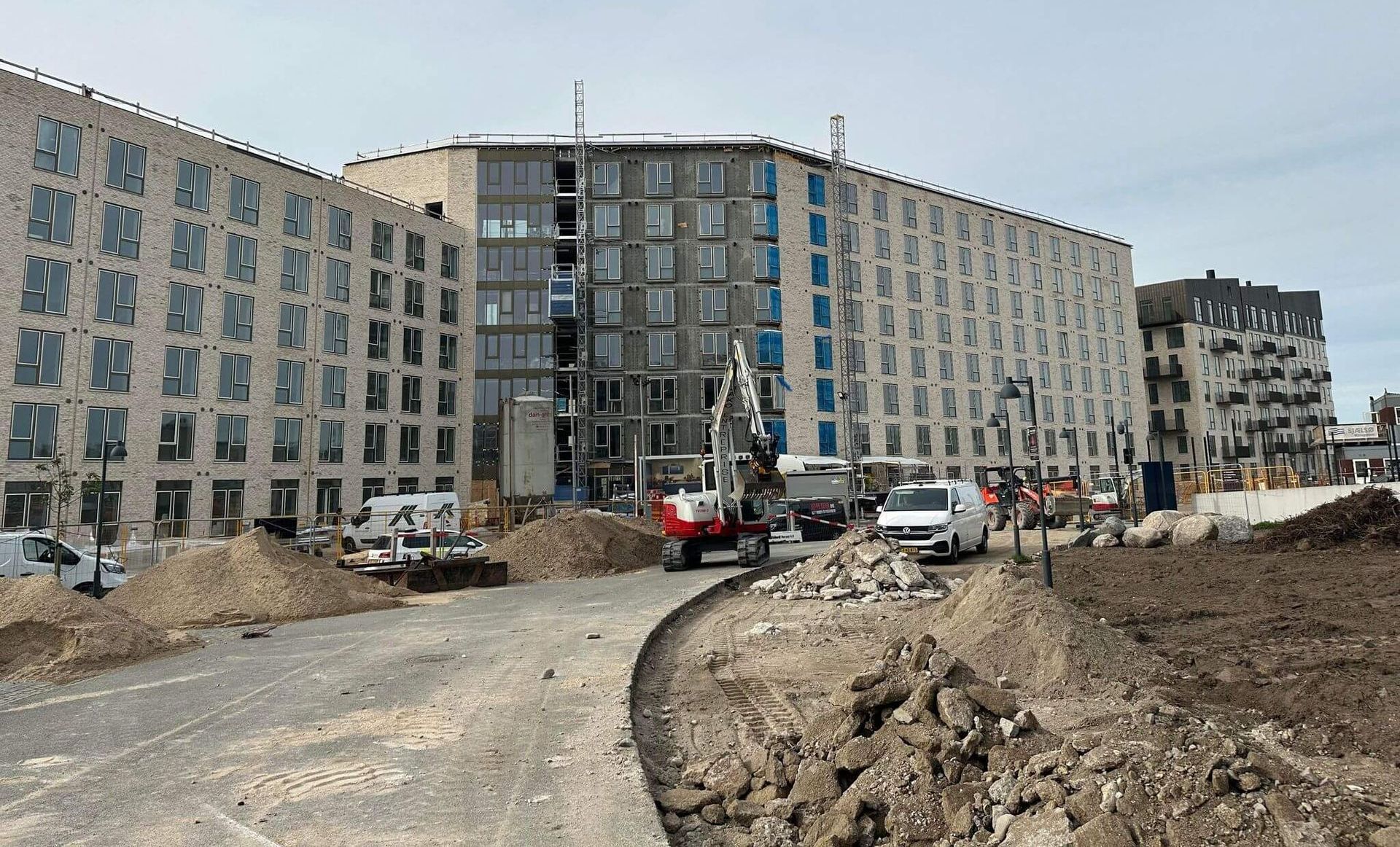 En stor bygning bygges ved siden af en grusvej.