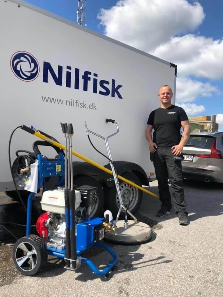 En mand står foran en nilfisk trailer