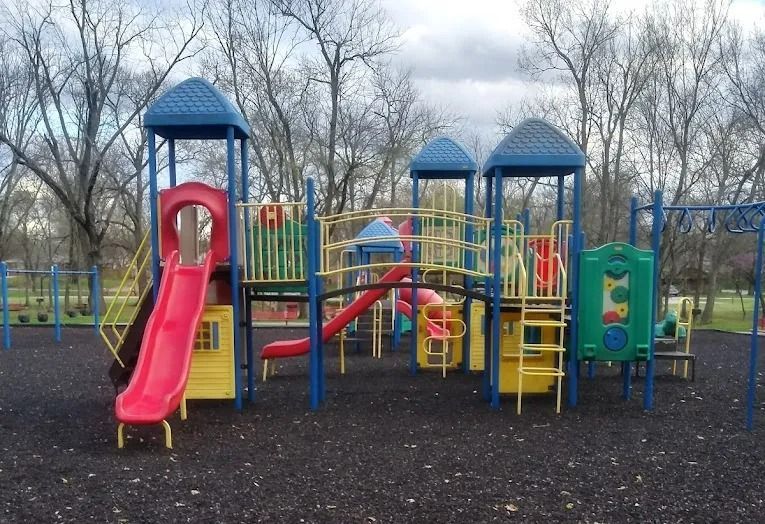 Playground with red slides, blue towers, yellow structures, and black ground.