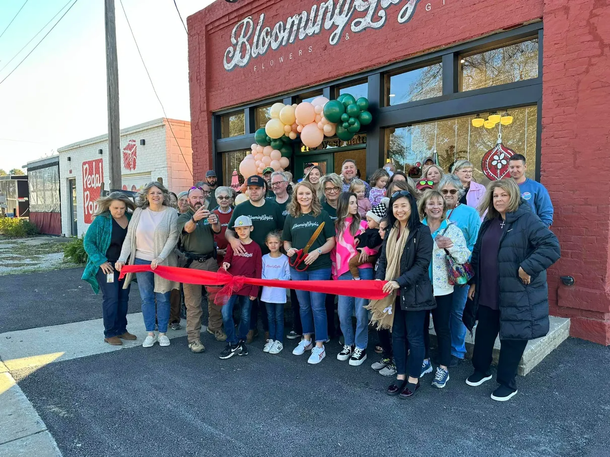 Group cuts ribbon at Blooming Lily storefront grand opening.
