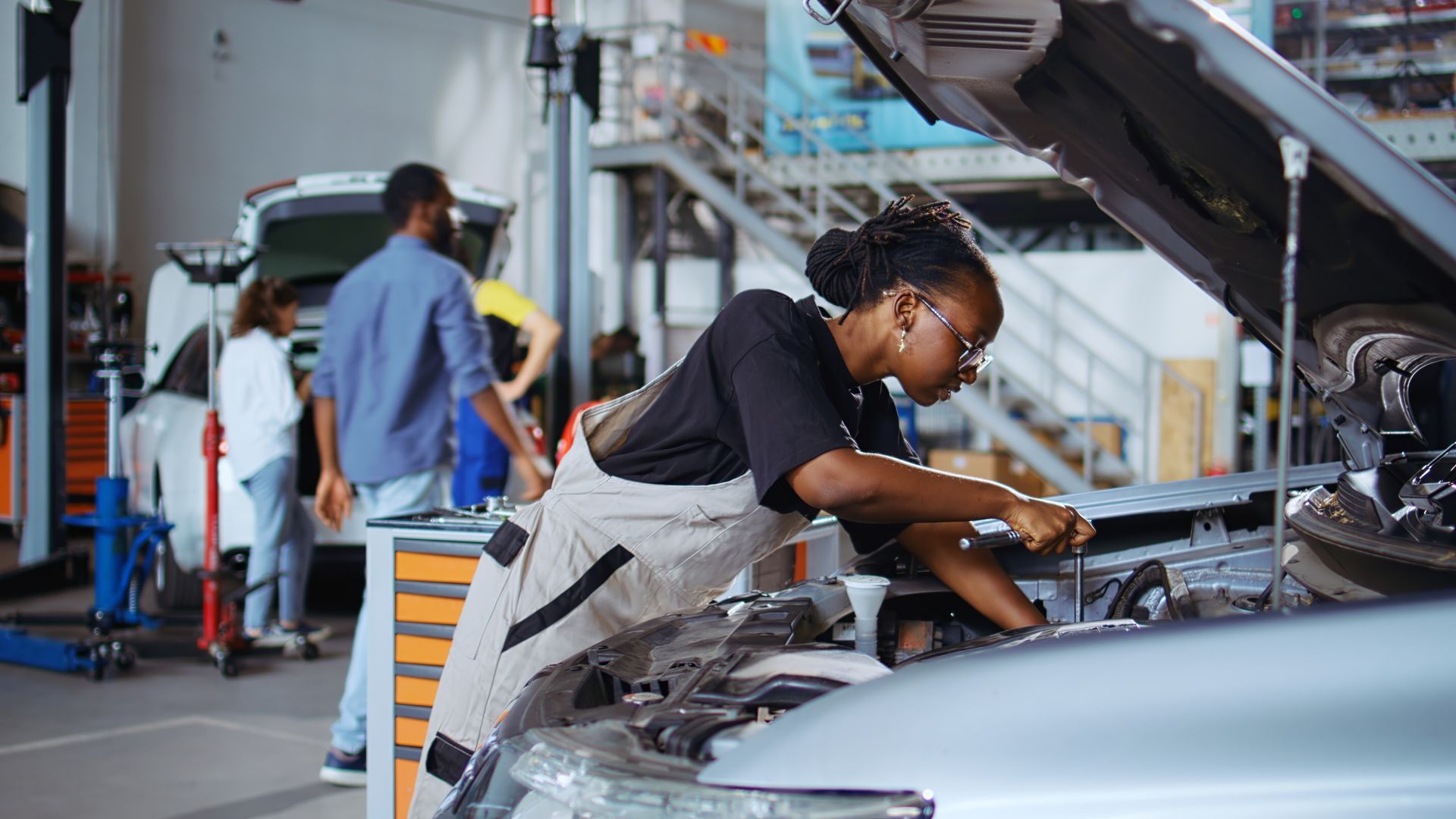 Mechanic testing a car battery with a diagnostic tool under the hood of a vehicle.