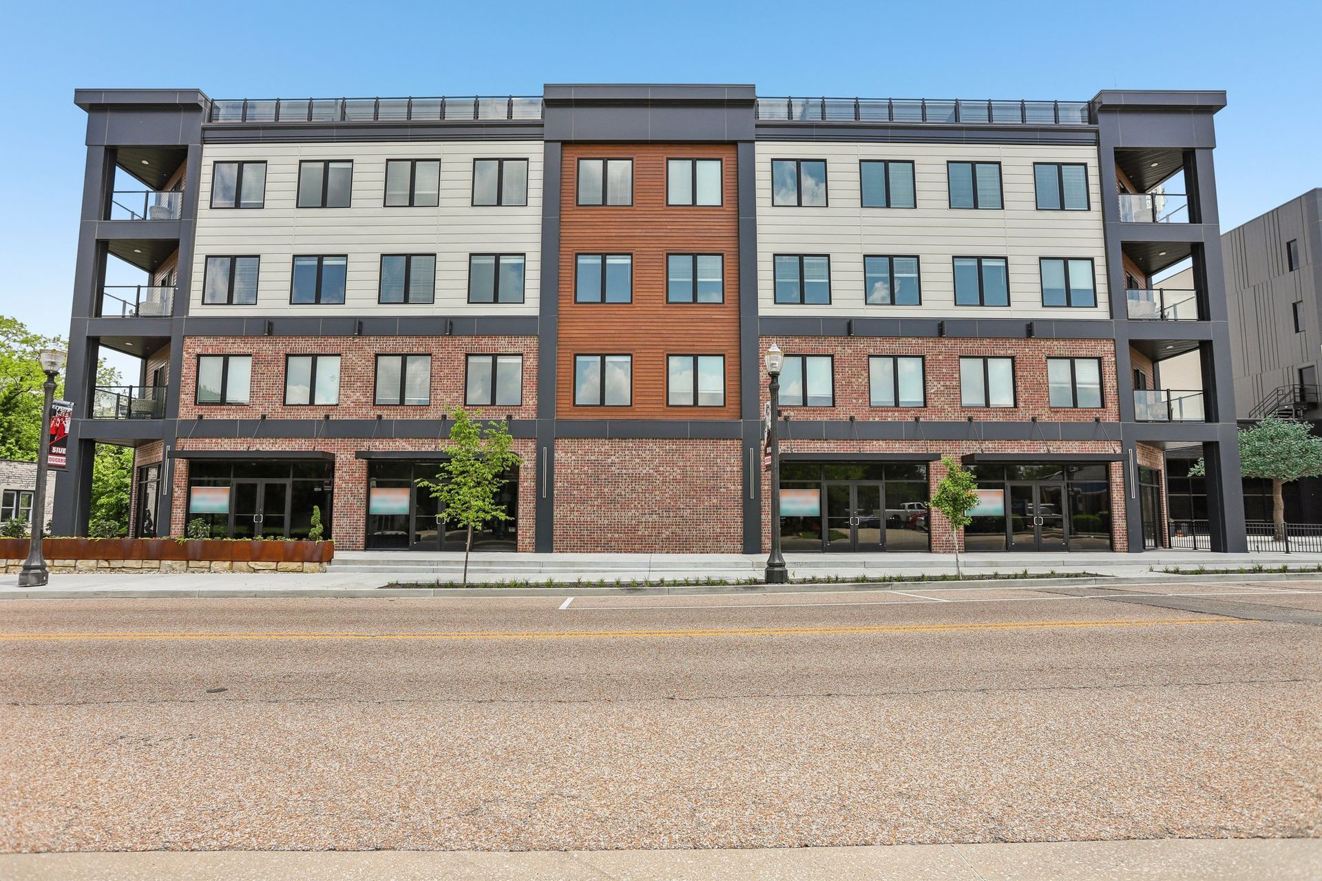 A large building with a lot of windows is on the corner of a street.