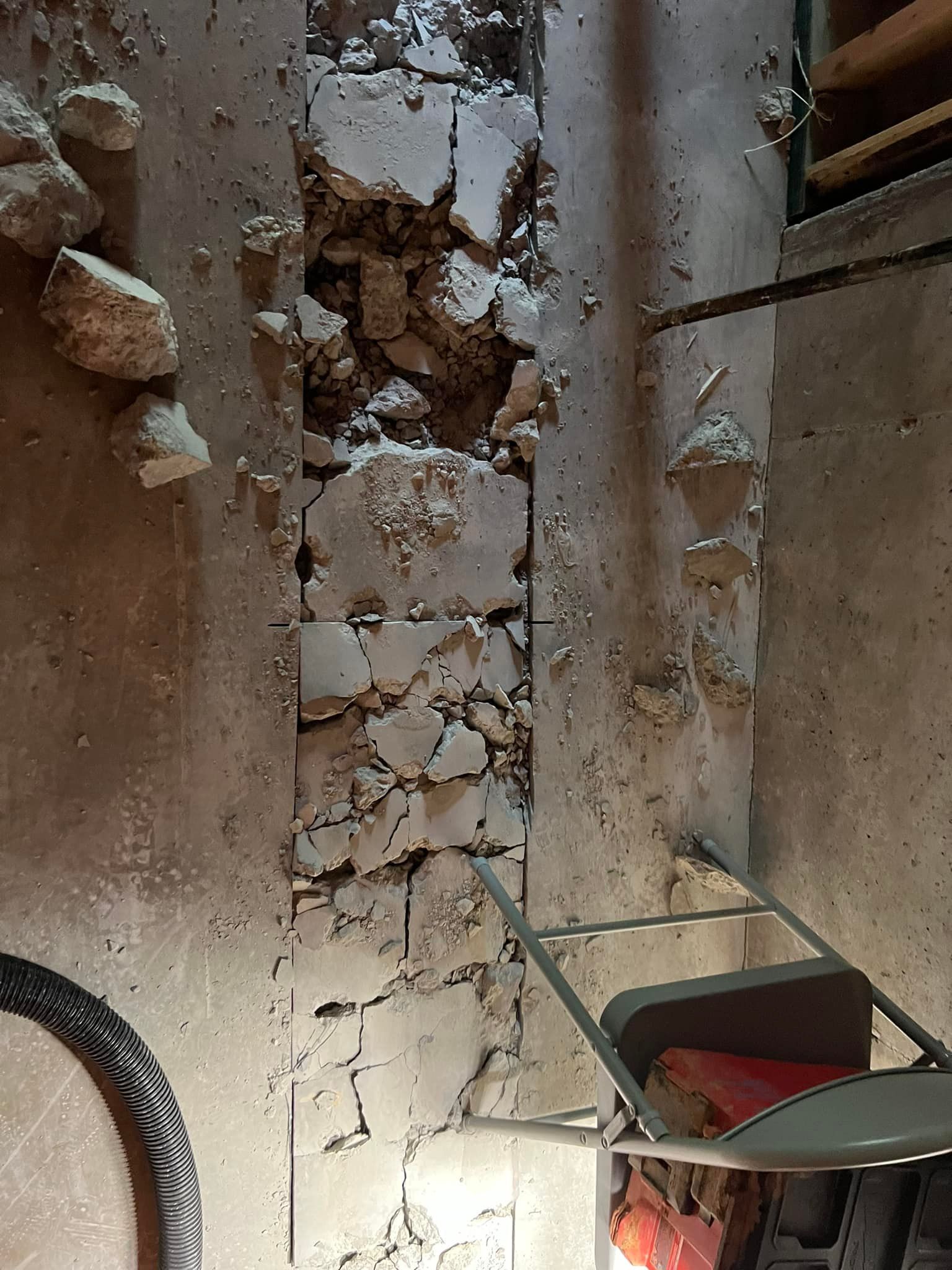 A concrete wall with a hole in it is being demolished.