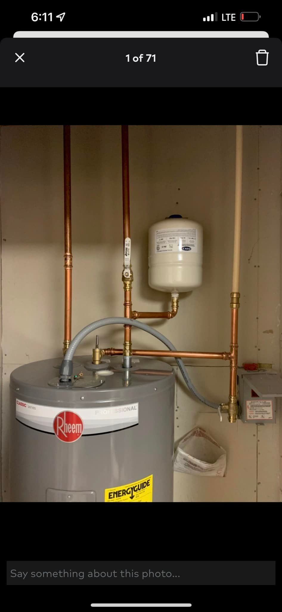 A picture of a water heater in a room with copper pipes.