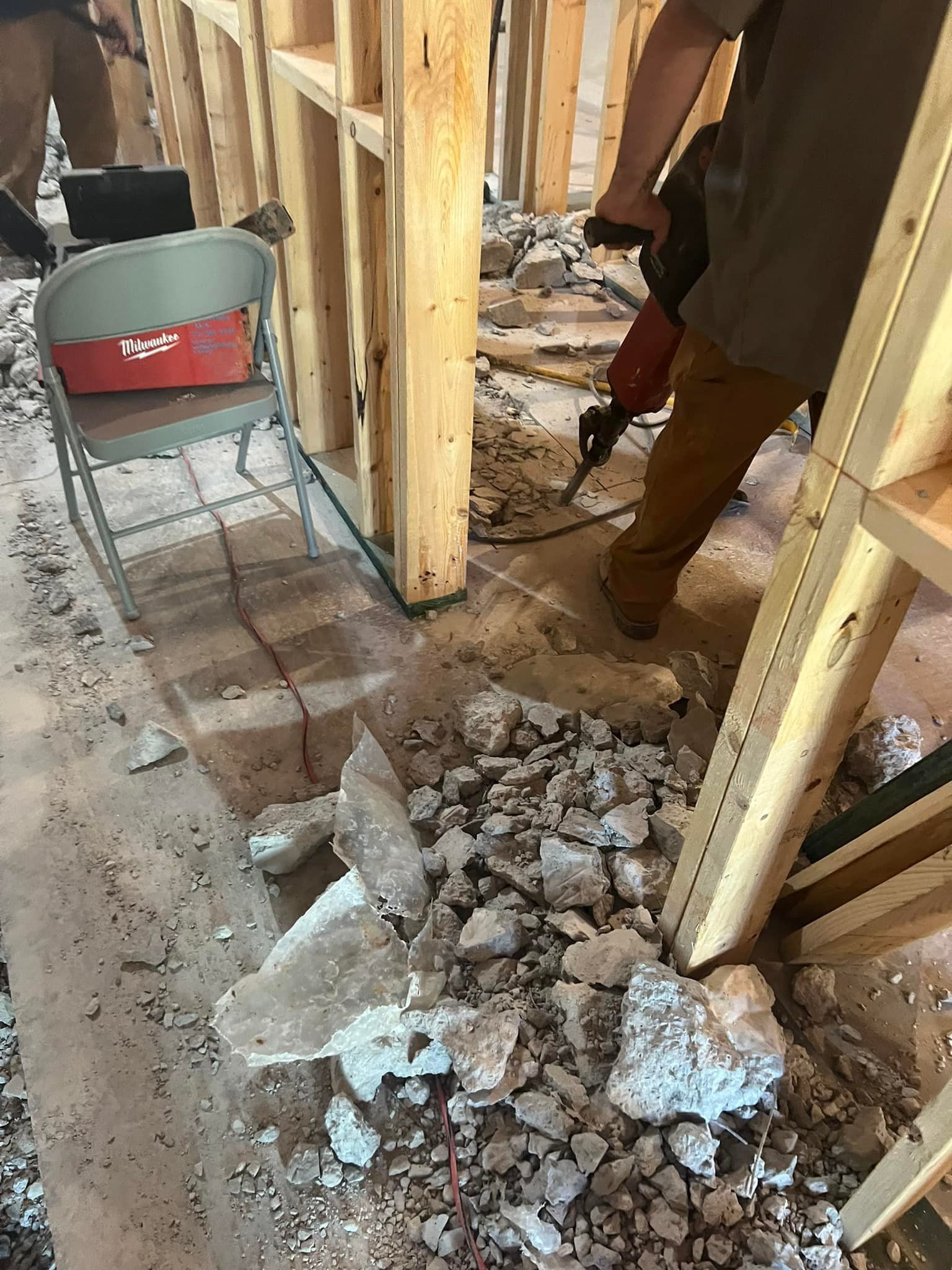 A man is using a hammer to break up concrete in a room.