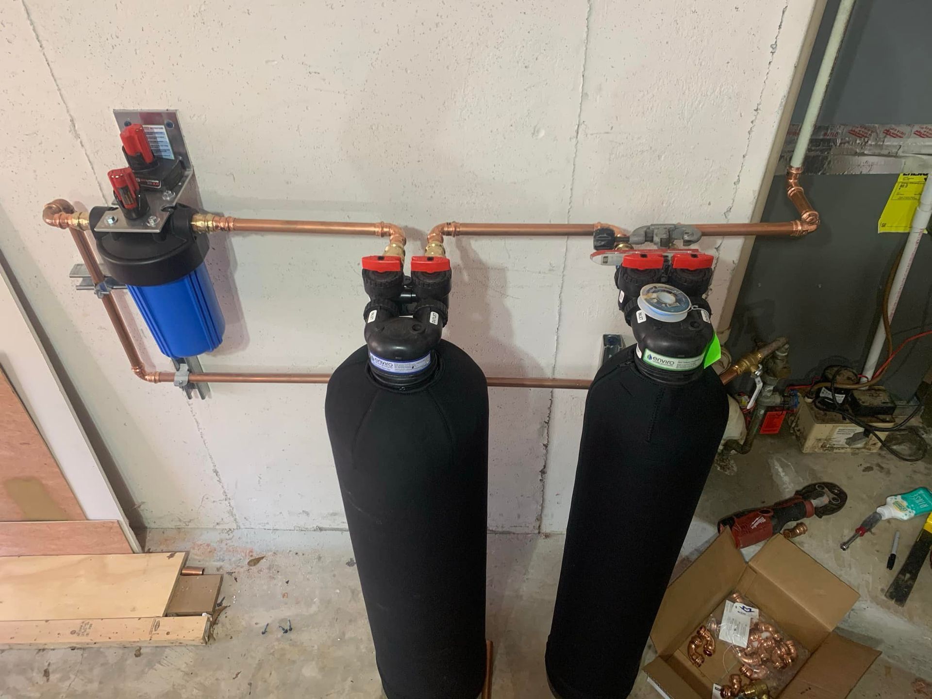 Two water filters are connected to a copper pipe on a wall.