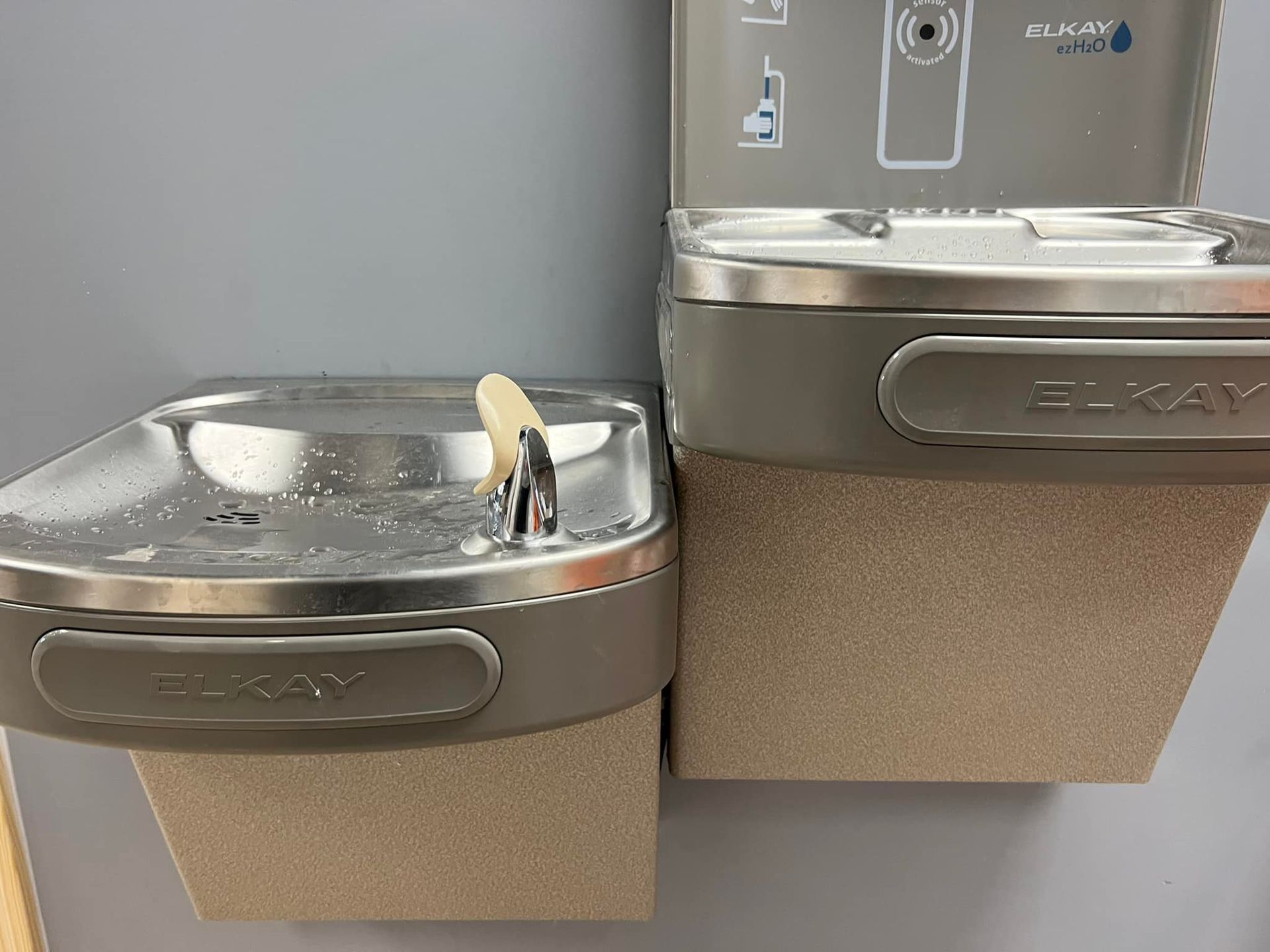 A stainless steel water fountain with a soap dispenser attached to it.