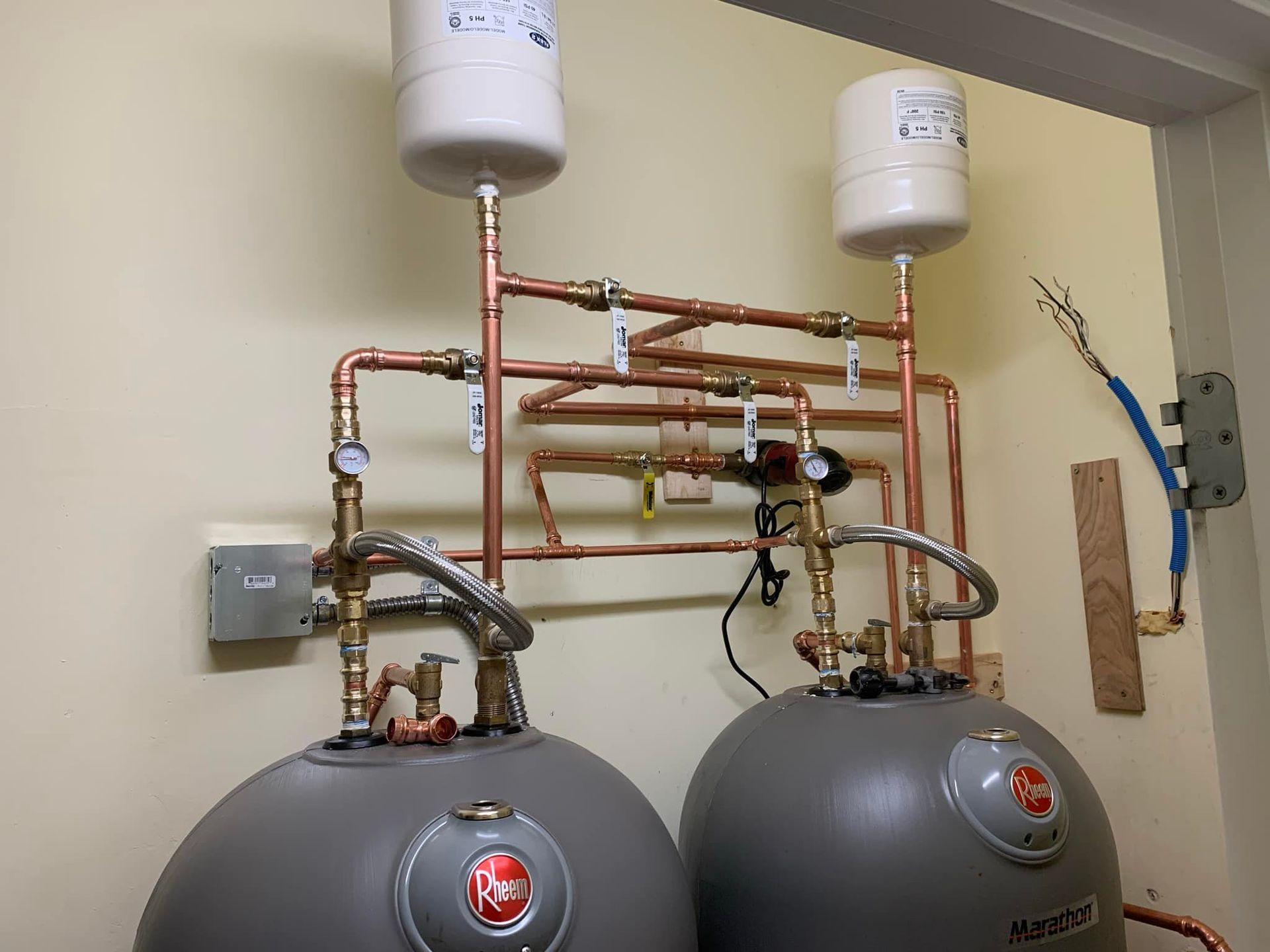 Two water heaters are sitting next to each other on a wall.