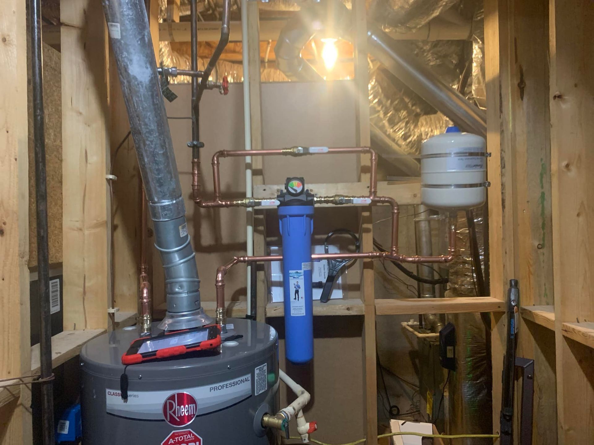 A water heater is sitting in a basement next to pipes.