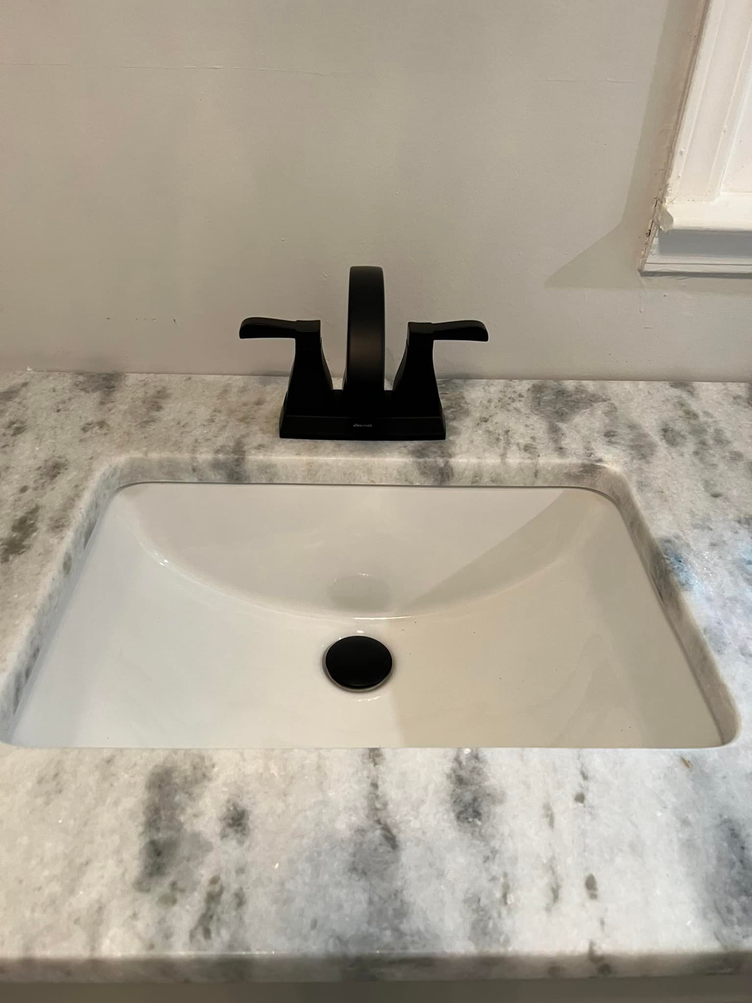 A bathroom sink with a black faucet on a marble counter top.