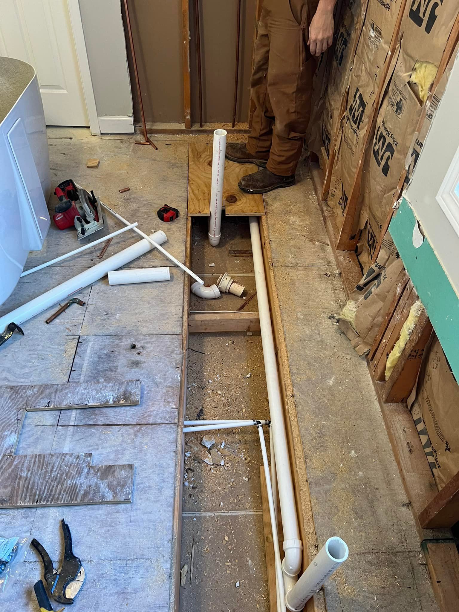 A man is standing next to a hole in the floor in a bathroom.