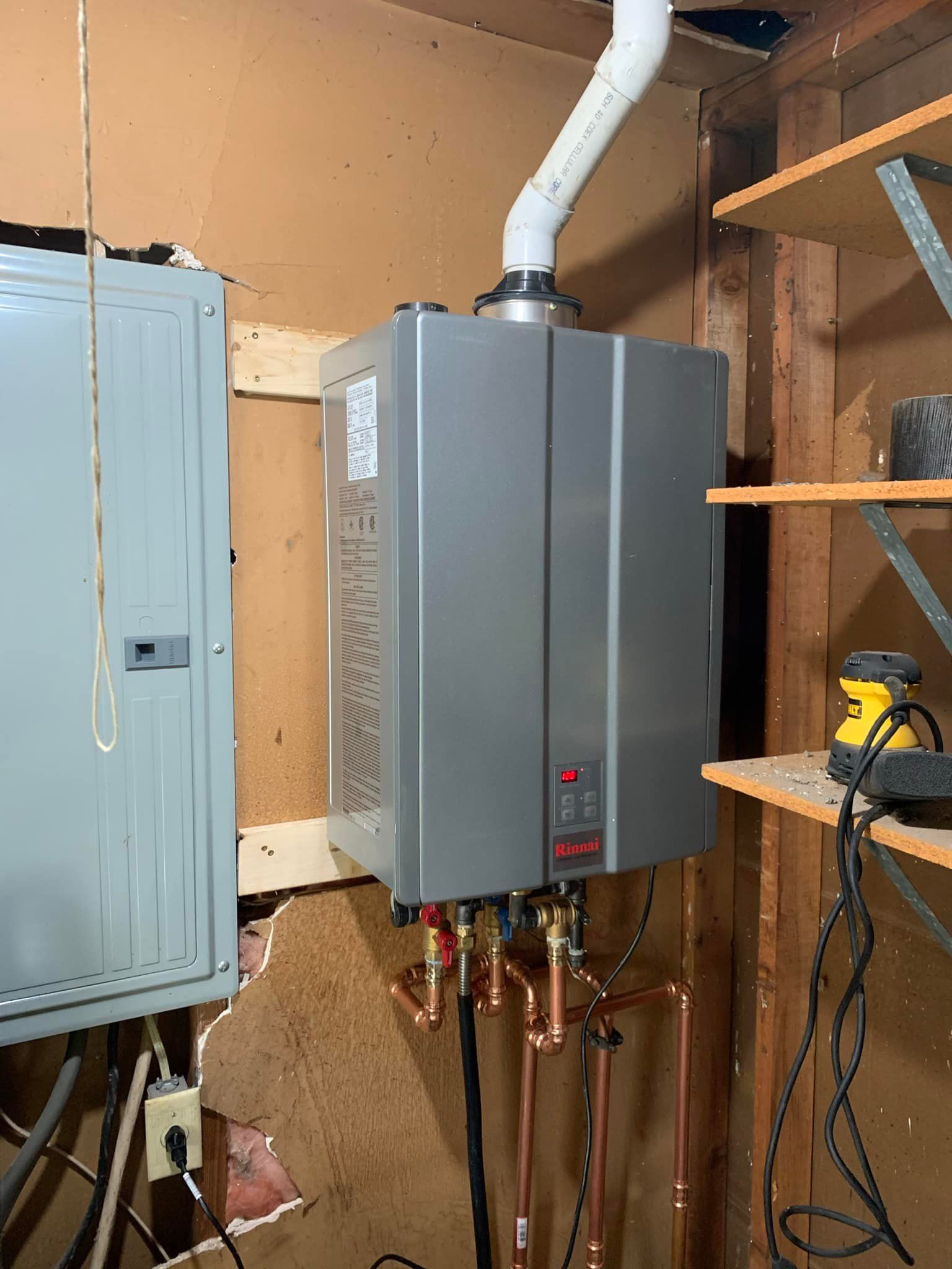 A water heater is sitting in a room next to a shelf.