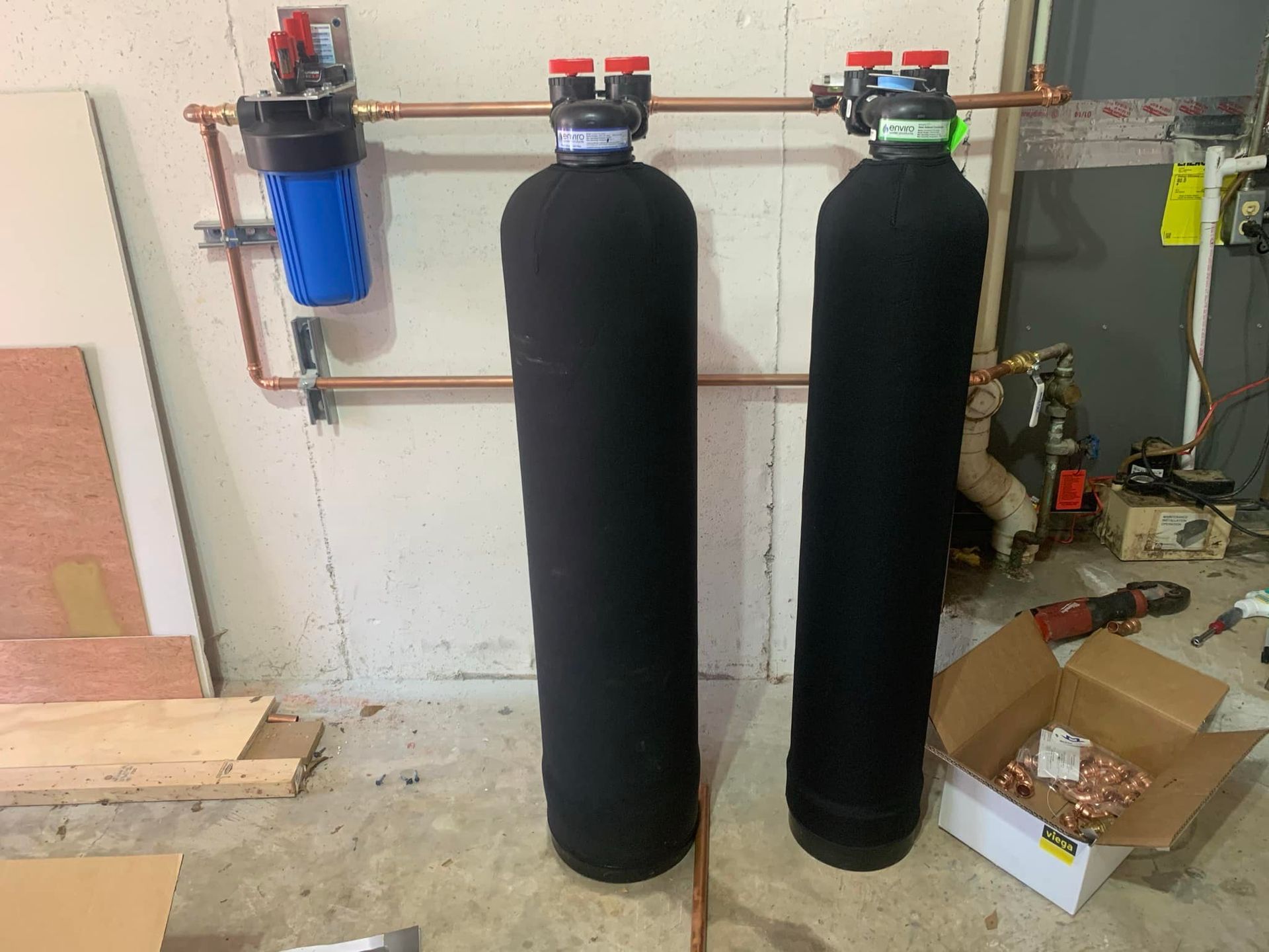 Two water filters are sitting next to each other in a garage.