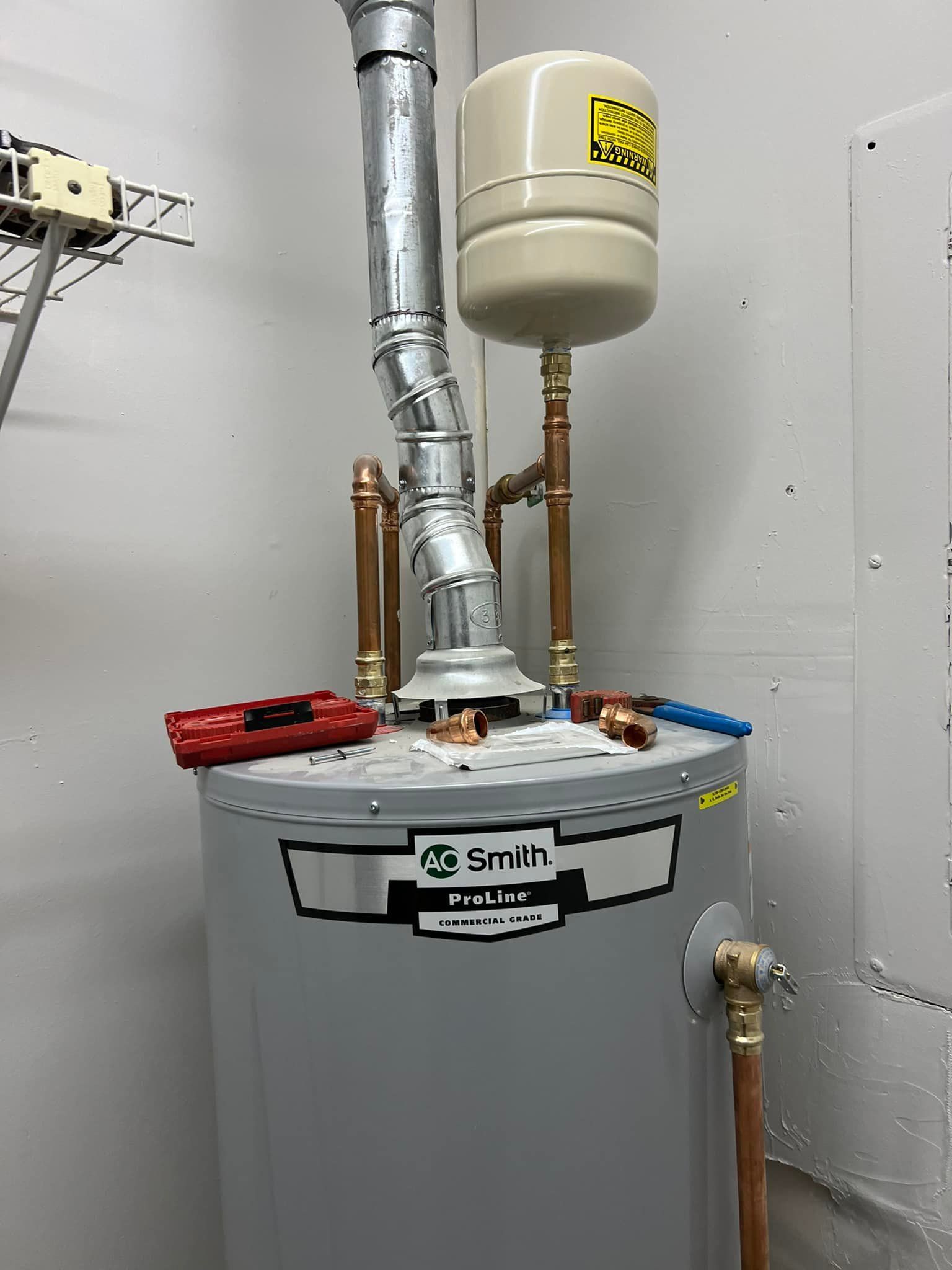 A water heater is sitting in a room next to a wall.