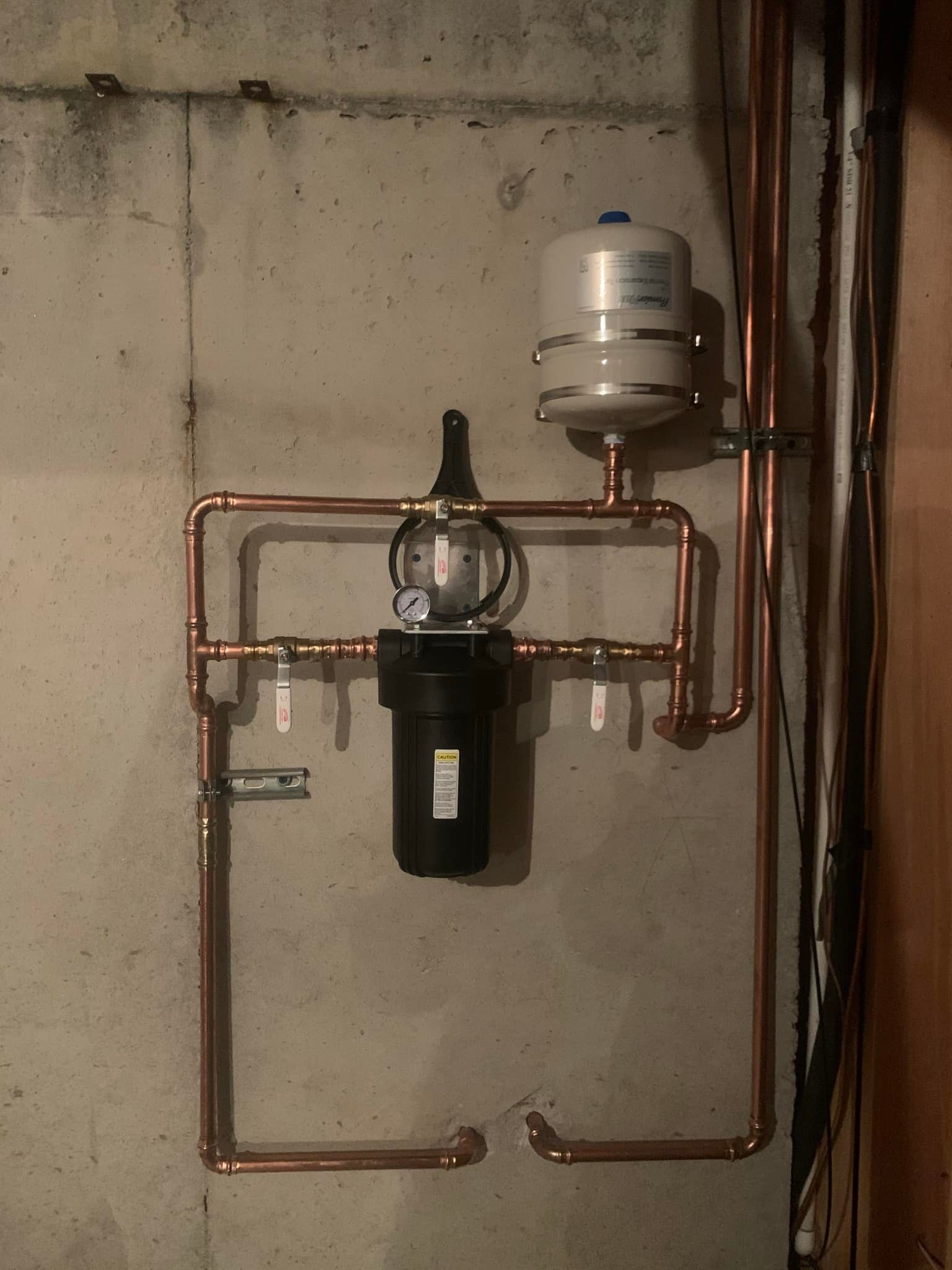 A copper pipe with a tank attached to it