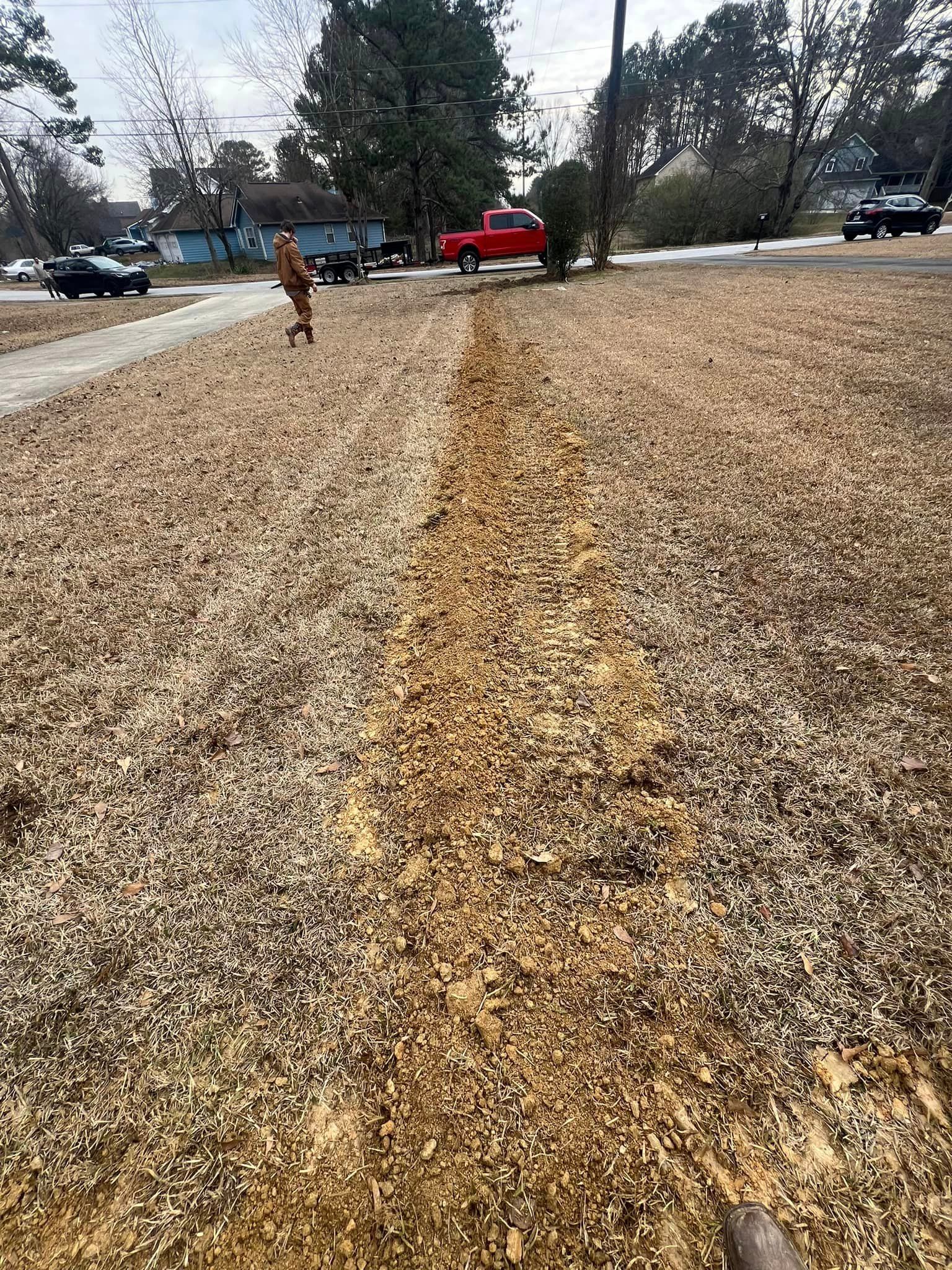 A red truck is parked on the side of the road next to a pile of wood chips.