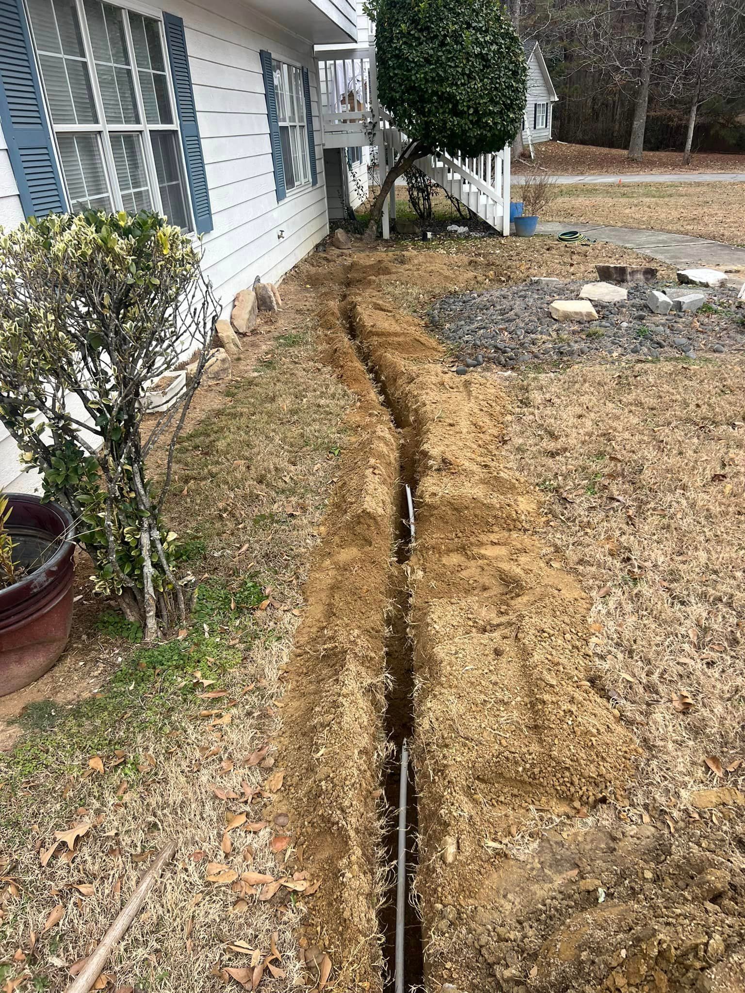 A large hole in the ground in front of a house.