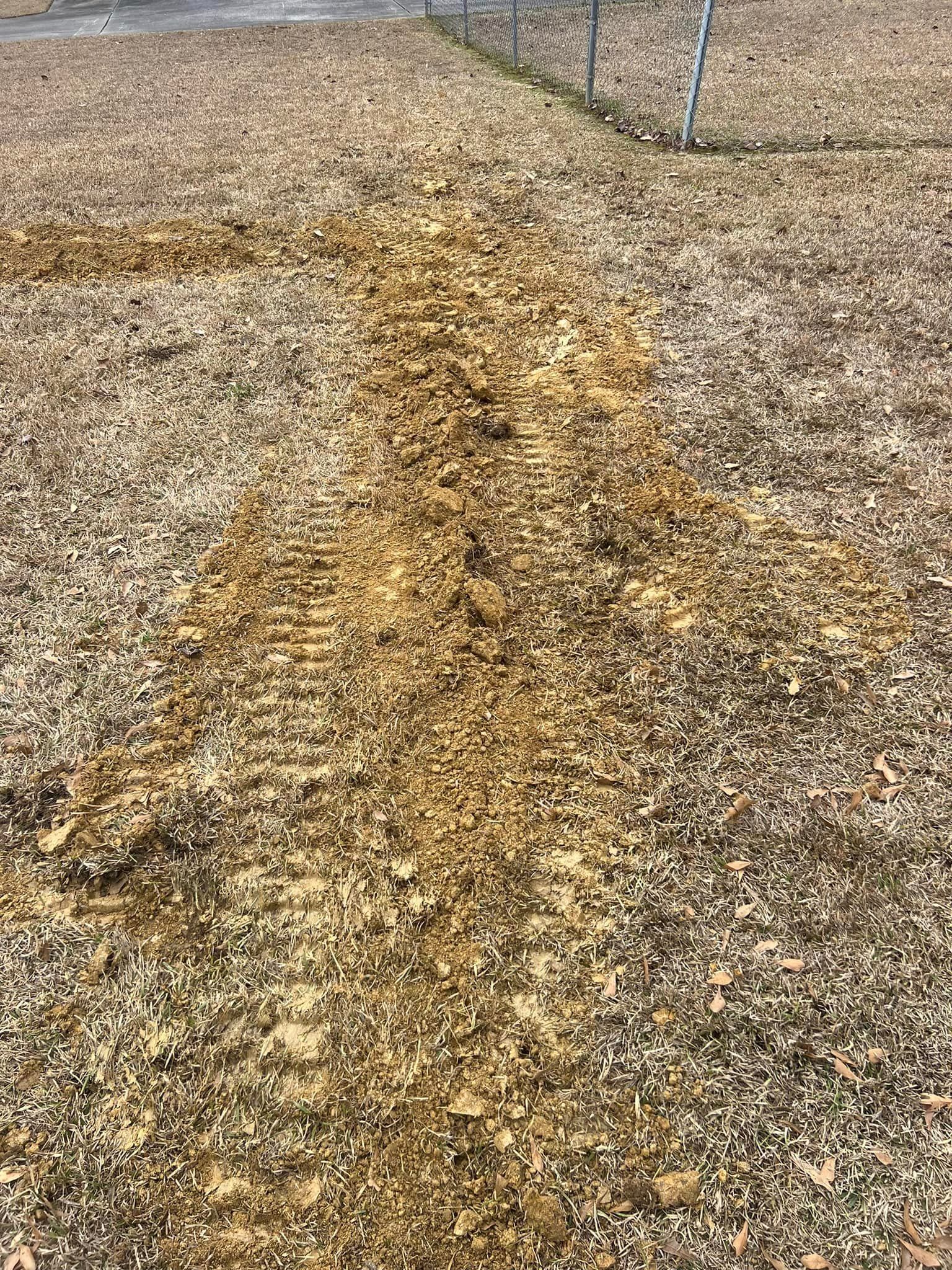 A pile of wood chips in a field next to a fence.