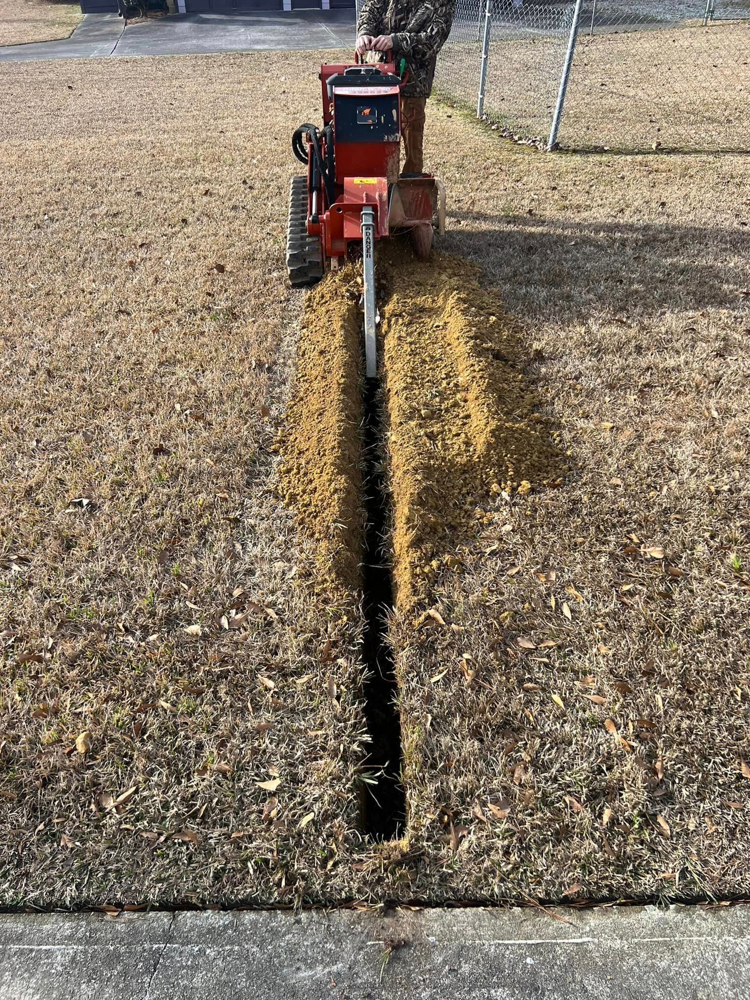 A tractor is digging a trench in the grass.