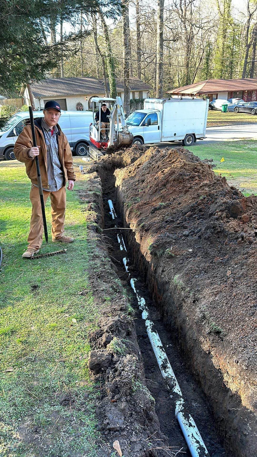 A man is standing next to a pipe in the dirt.