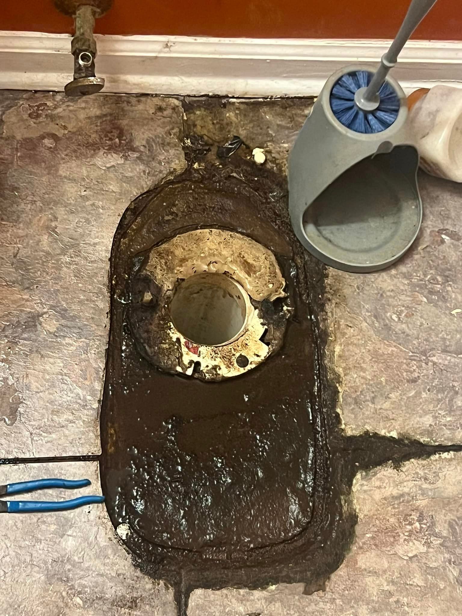 A toilet bowl sitting on top of a dirty floor next to a toilet brush.