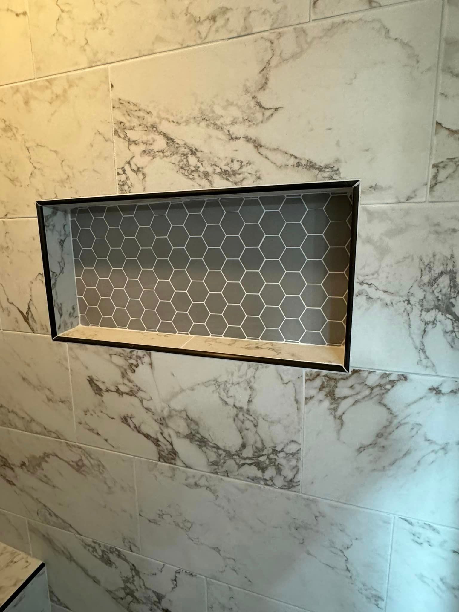 A shower niche is being built into a marble wall.