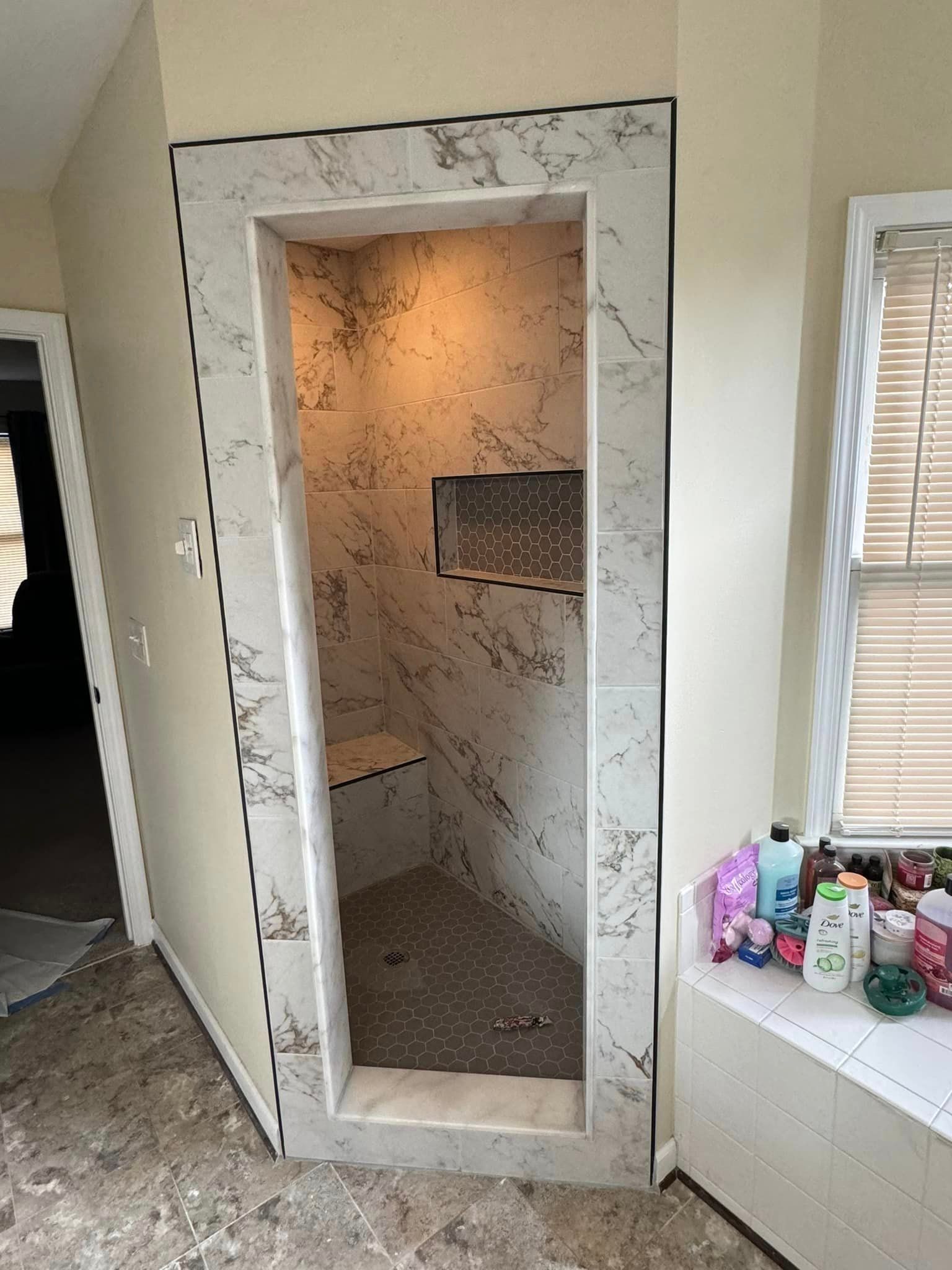 A bathroom with a walk in shower and a window.