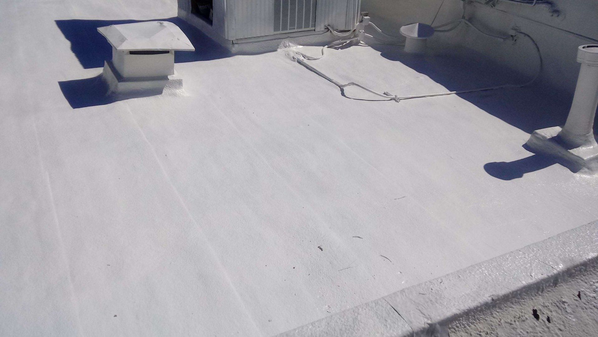 A white roof with a small vent and a shadow from a sunny day.