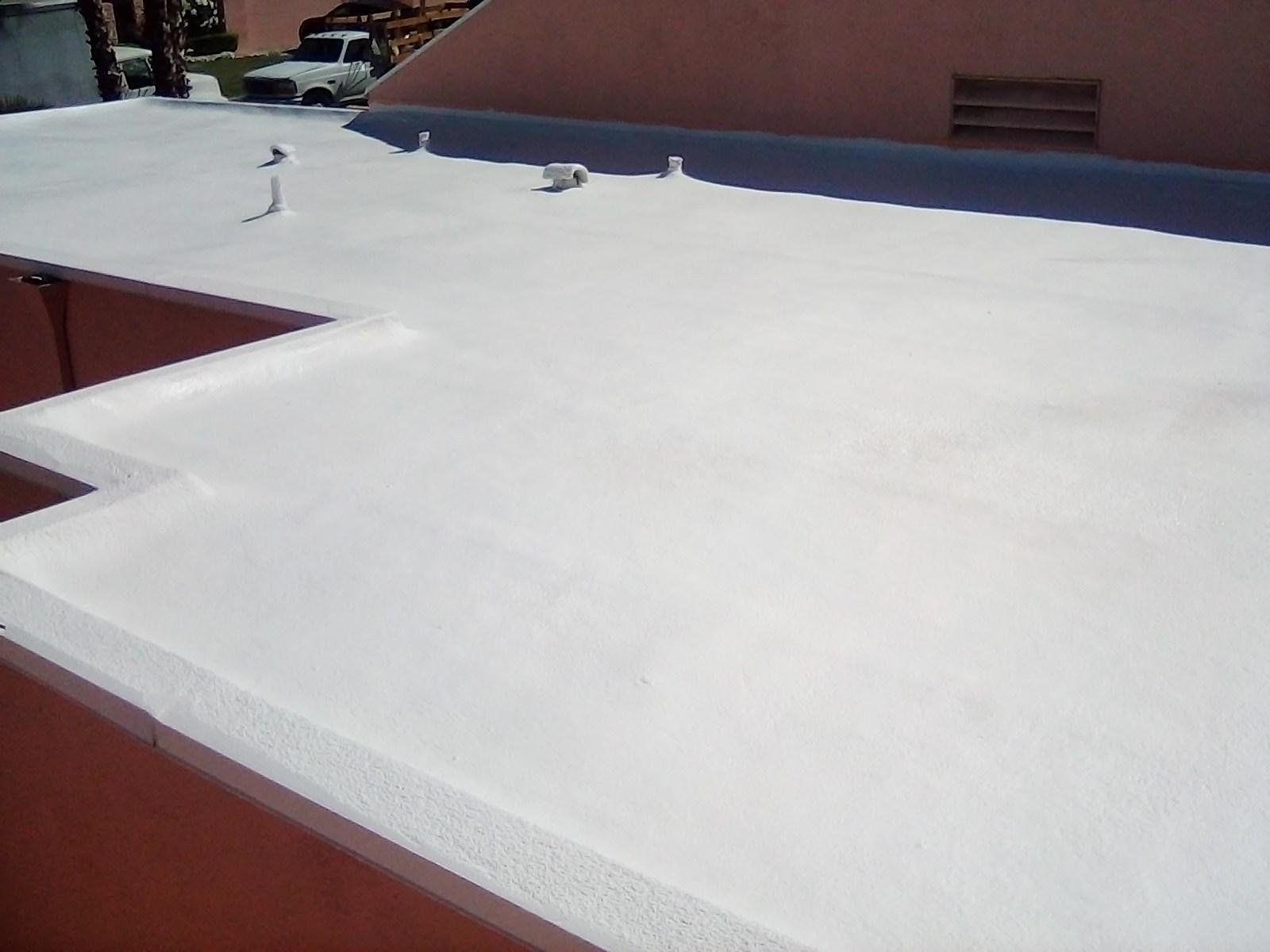 White flat roof on a red building under a clear sky. A truck is visible in the background.