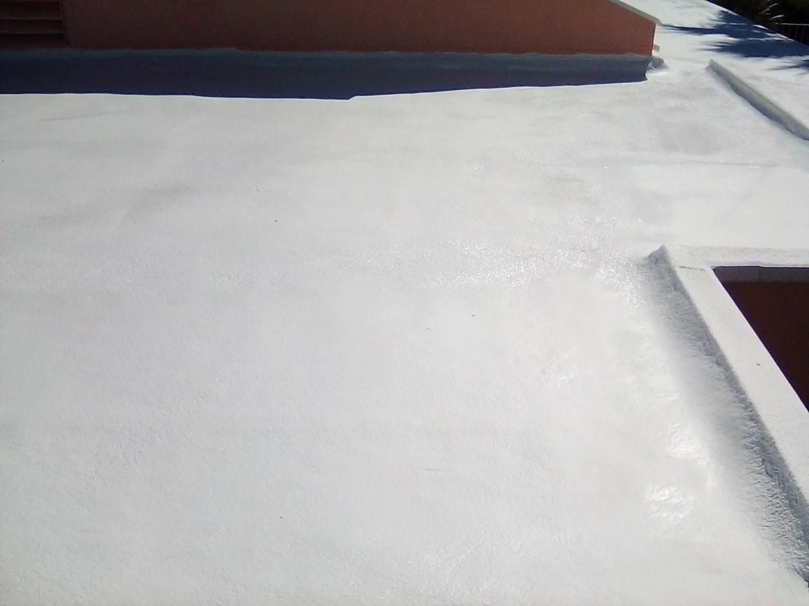 White, painted flat roof with visible seams and a small wall in the corner. The building has a neutral, pale-orange exterior.