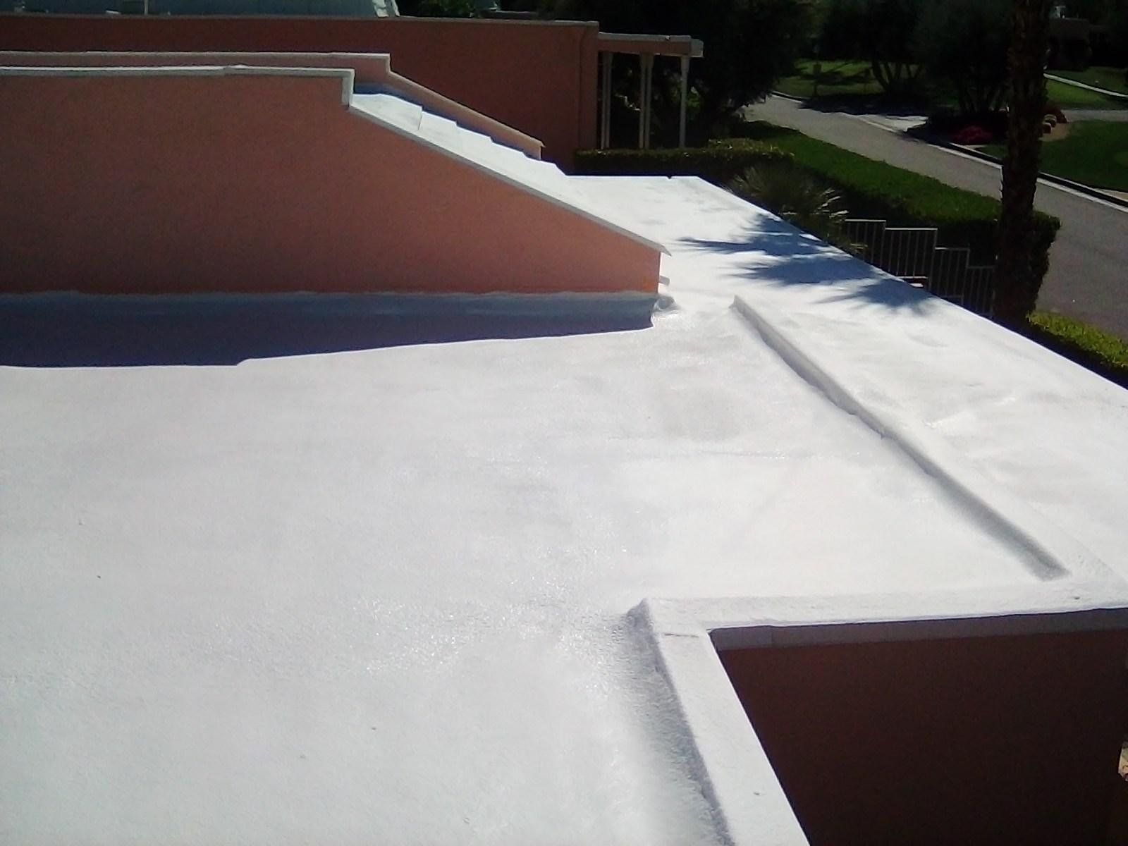 A flat, white-painted roof with a pink stucco wall on a sunny day. The roof has geometric shapes.