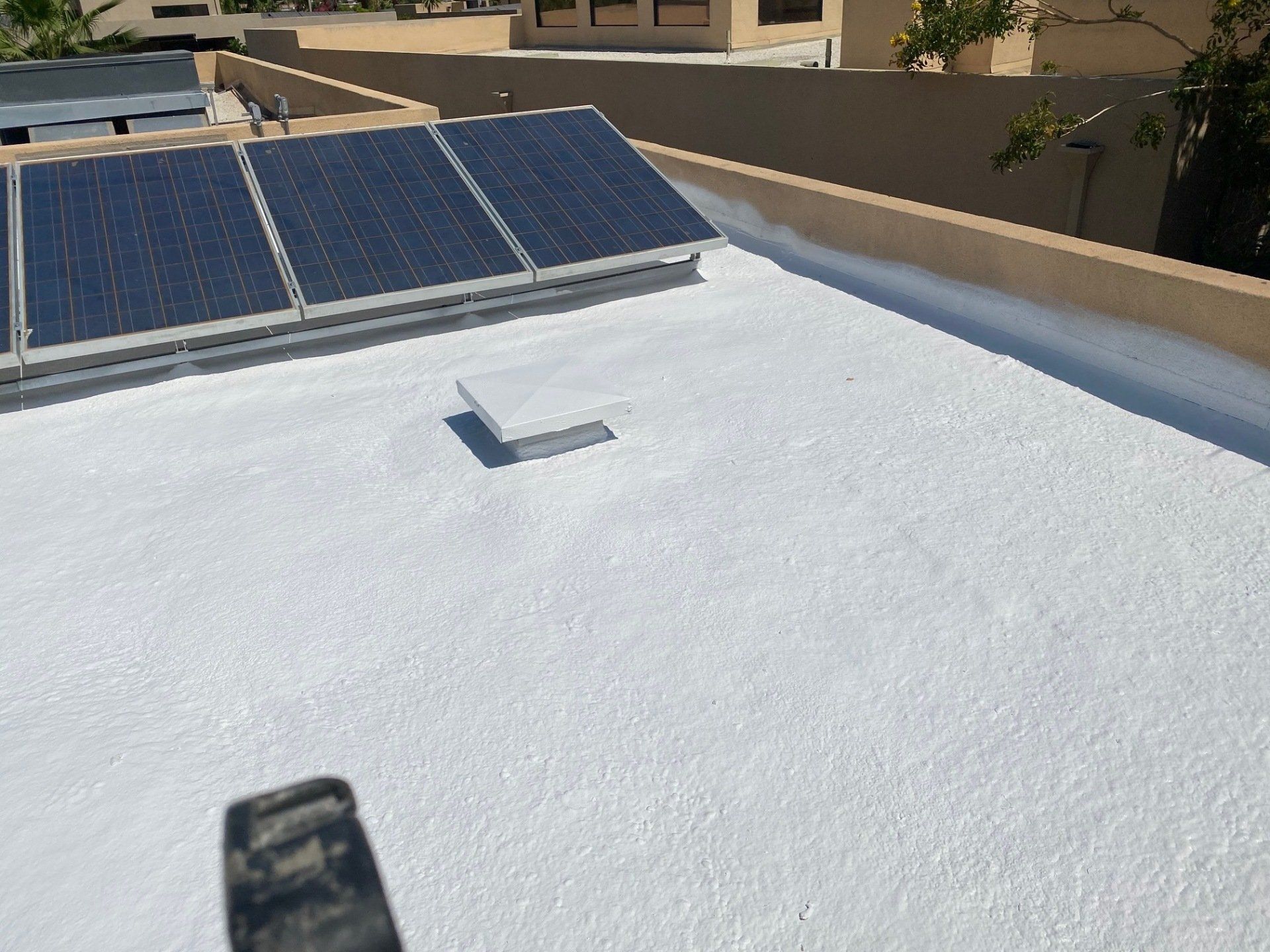 A flat, white roof with solar panels and a small vent. The building has a beige perimeter wall.