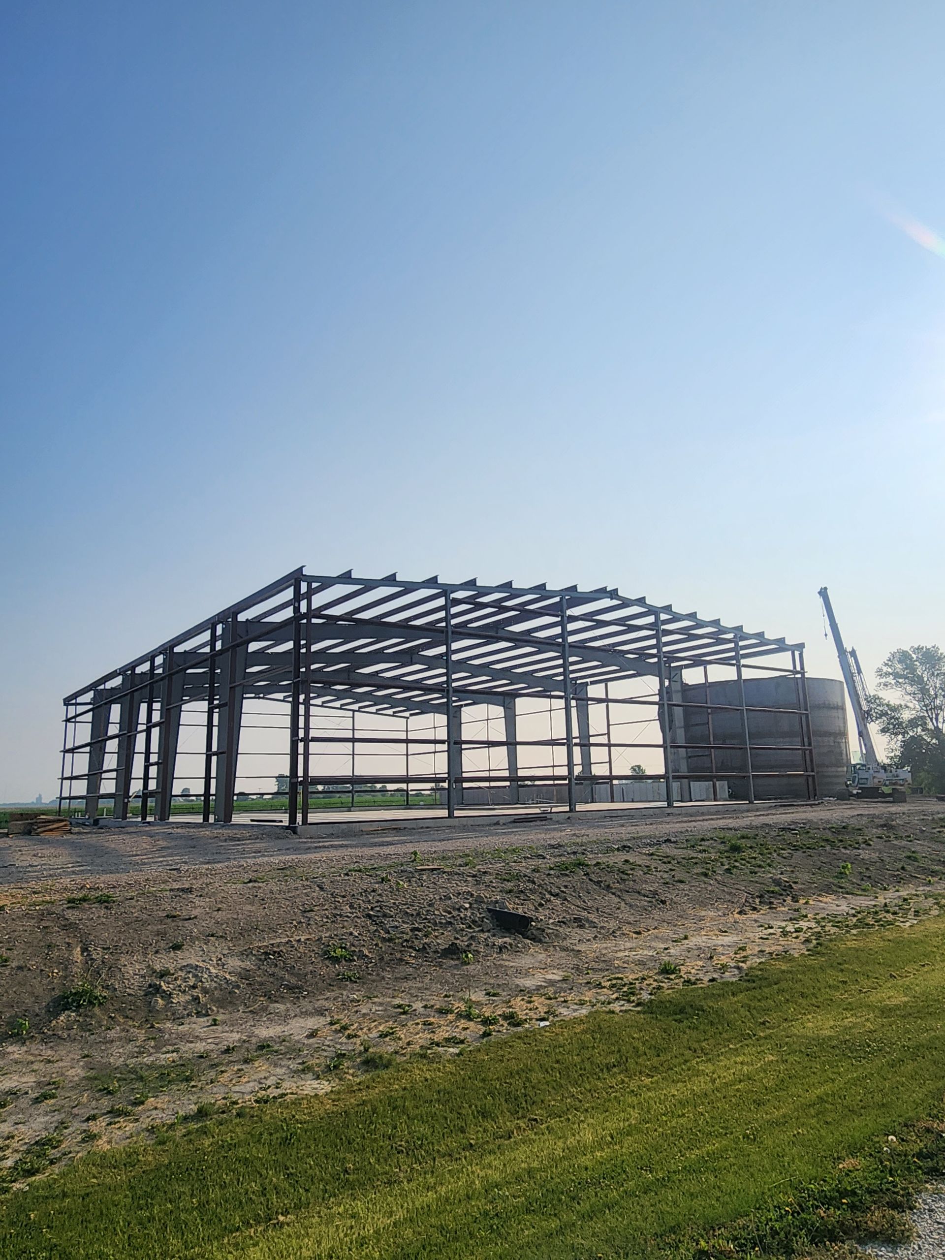 Steel frame of a building under construction, with visible beams and supports, set against a blue sky. Steel frame of a building under construction, with visible beams and supports, set against a blue sky.