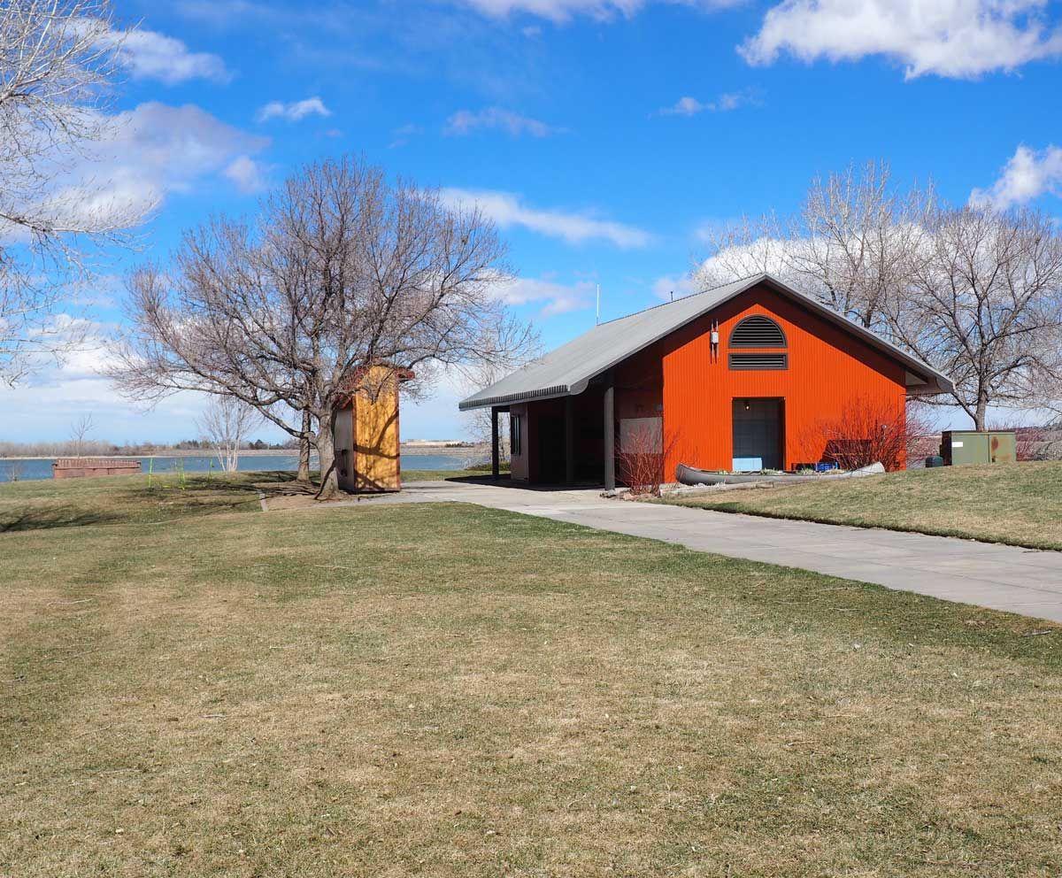 Orange building with a dark roof on a grassy area, trees, and a blue sky. Orange building with a dark roof on a grassy area, trees, and a blue sky.