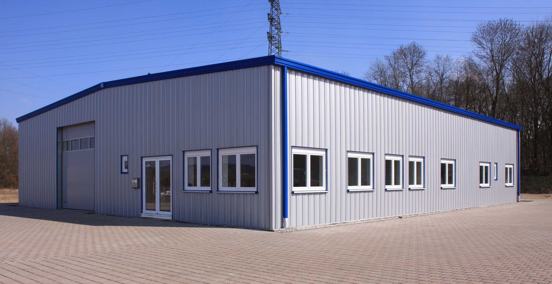 Metal building with blue trim and windows under a clear sky.
