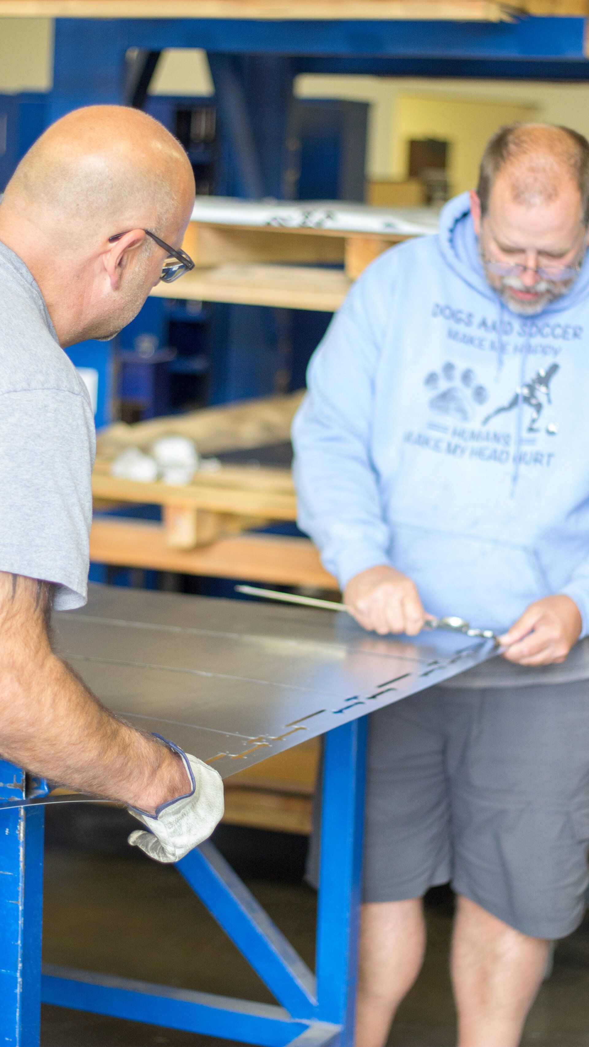 Two men are working on a piece of metal in a factory.