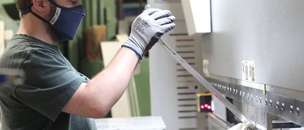 A man wearing a mask and gloves is working on a machine.