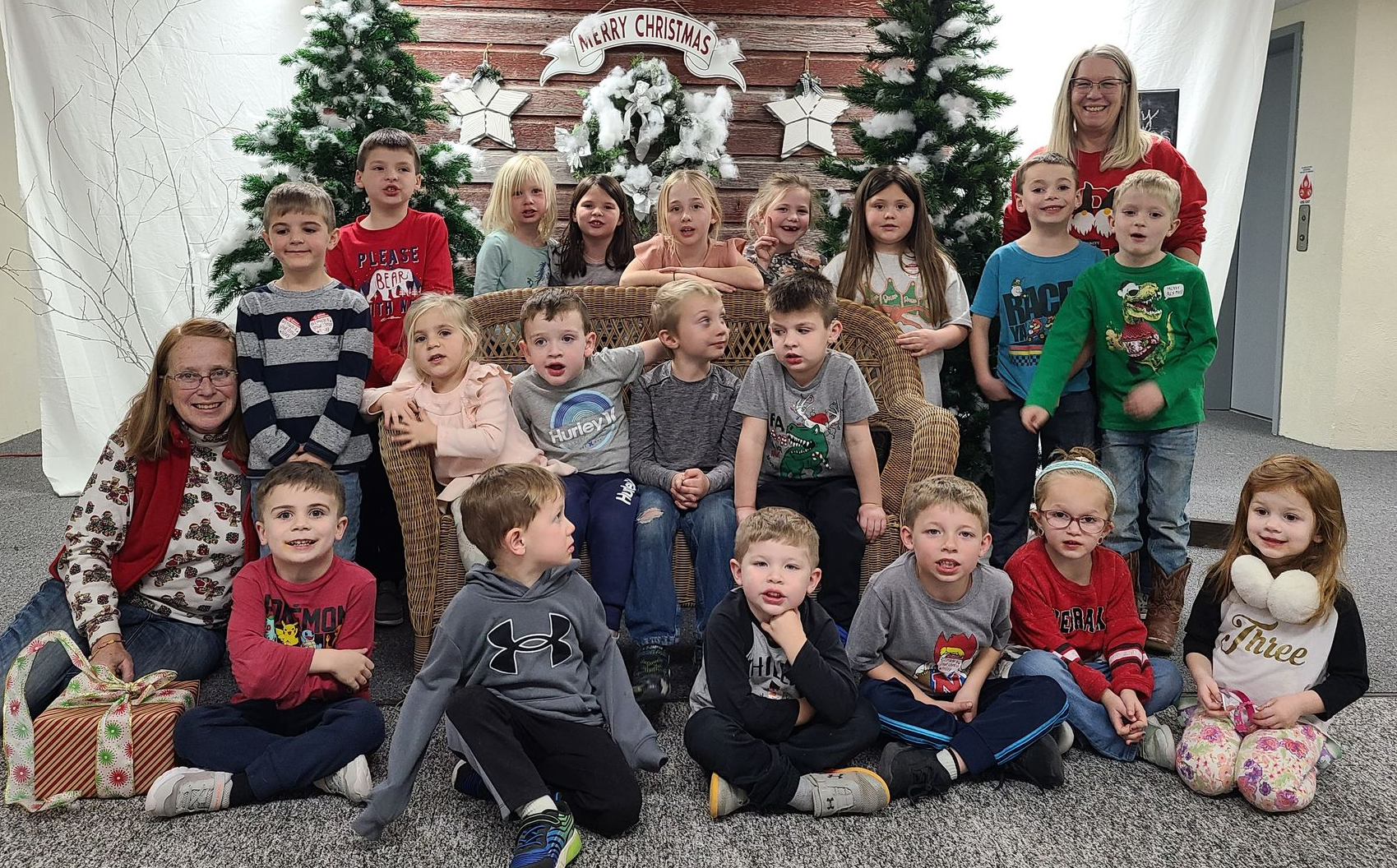 A group of children are posing for a picture in front of a christmas tree during Worship on Wednesday.