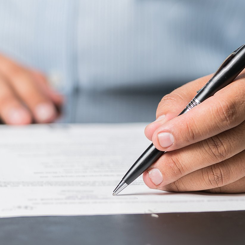 Hand writing with a pen on a document.