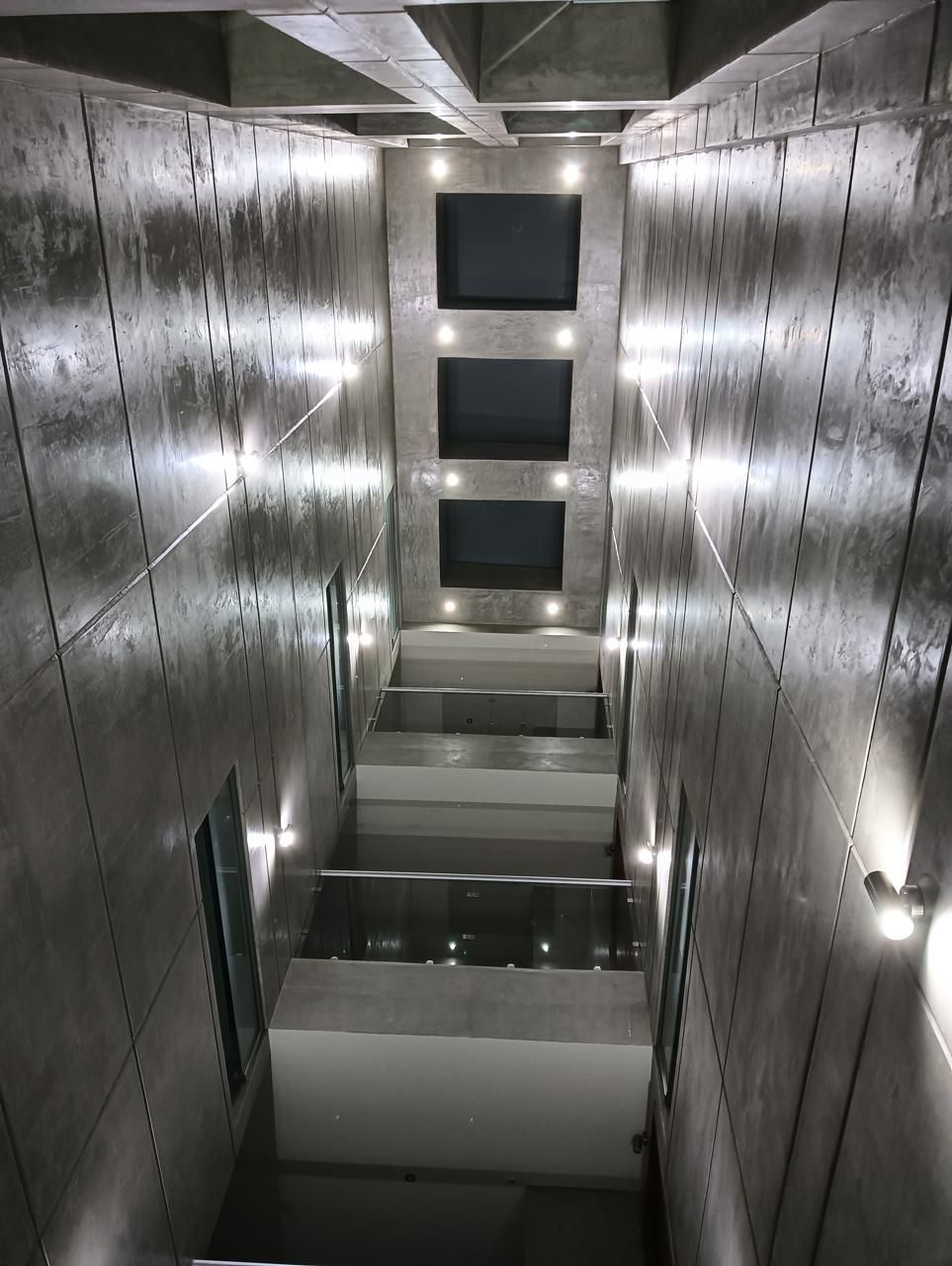 Escalera de hormigón en edificio moderno con barandillas de cristal e iluminación empotrada.