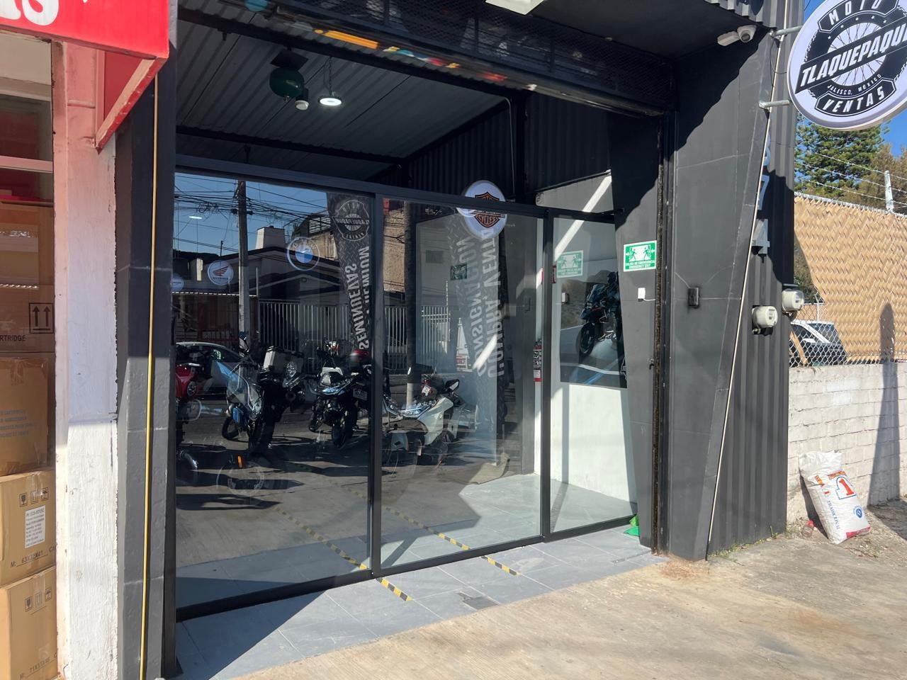 Exterior de tienda de motos con escaparates de cristal y varias motos en exposición.