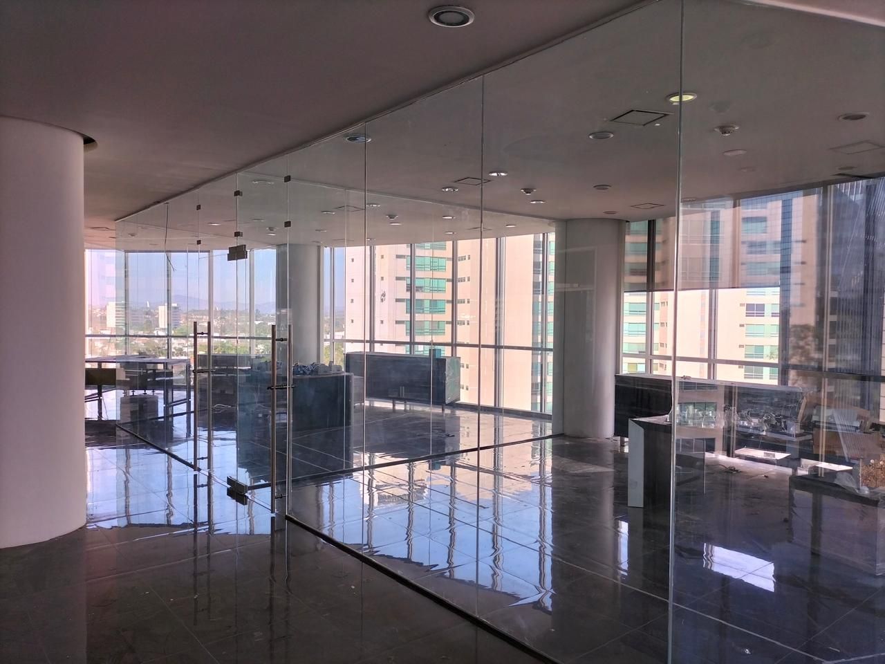 Espacio de oficina vacío con grandes ventanales con vistas a la ciudad, suelo brillante y paredes de cristal.