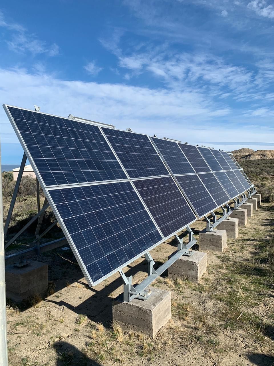 Paneles solares sobre bloques de hormigón en un campo, bajo un cielo azul.